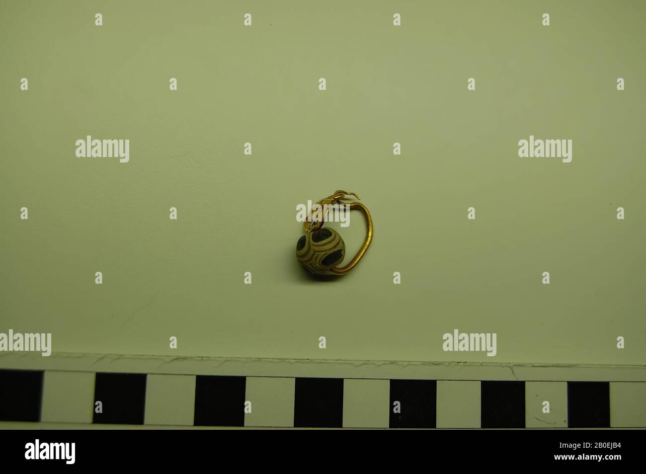Un orecchino dorato con uno scudo piatto ovale dorato con due mezzane pressate sul davanti e un occhio con vetro bianco opaco, decolorato e blu scuro, orecchino, oro e vetro, 2,0 x 1,5 cm, Russia Foto Stock