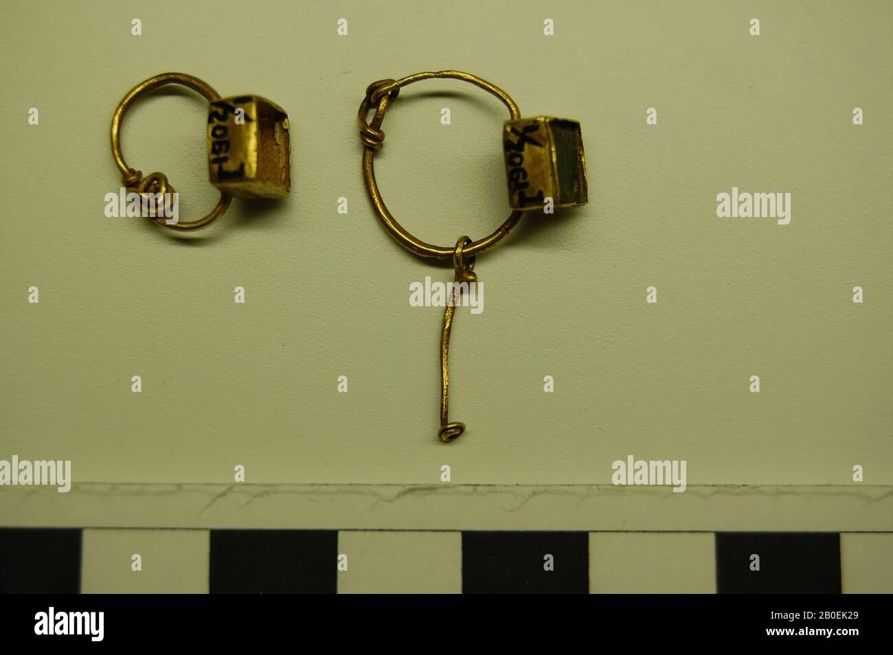 Auricolare con cassetta quadrata con vetro trasparente verde al suo interno, un filo d'oro sospeso diritto è fissato all'anello auricolare., auricolare, oro, 3,2 cm, 100 Foto Stock