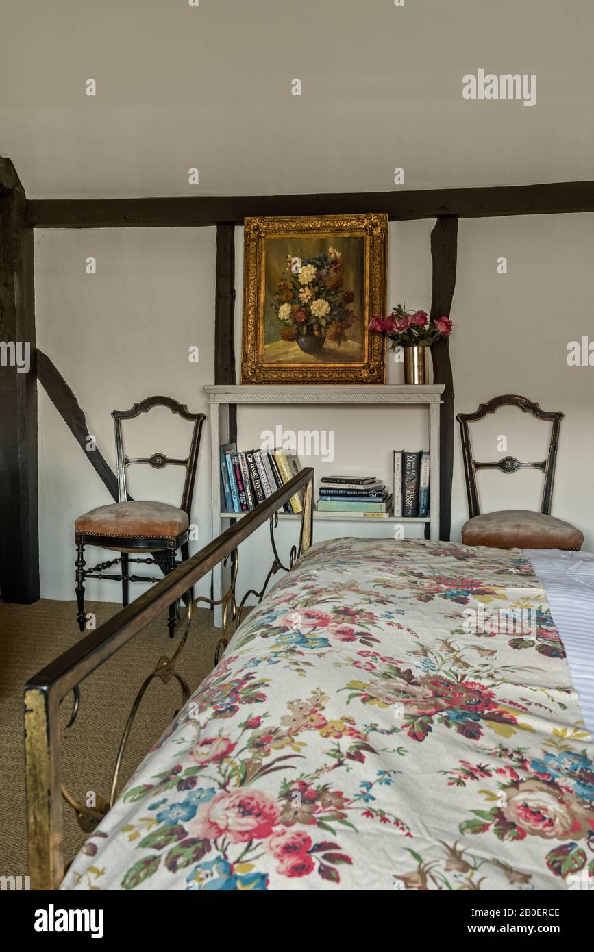 Poltrone laterali francesi con decorazioni su entrambi i lati della libreria con tessuto floreale vintage sul letto. Foto Stock