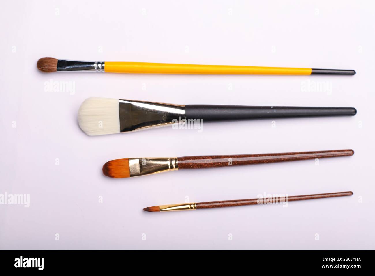 Pennelli d'arte di diverse dimensioni su sfondo bianco. Quattro spazzole per pittura, colpo di horisontal Foto Stock