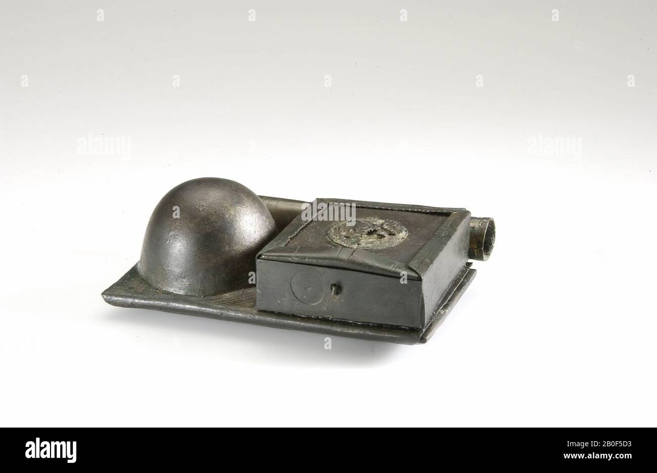 Scatola in bronzo unguento. Scatola rettangolare, chiusa per mezzo di uno scivolo quadrato piatto, decorata al centro con un medaglione in rilievo. La scatola, che non ha il fondo stesso, è bloccata su una piastra di fondo in bronzo. I bordi della piastra inferiore sono piegati sul retro, intorno a una tavoletta di ardesia con approssimativamente le stesse dimensioni che possono essere spinte fuori dal supporto di bronzo. Accanto alla scatola vi è una calotta sferica nella piastra inferiore, internamente cava. Lungo il lato della piastra di fondo è presente un tubo allungato (l 1891 Foto Stock