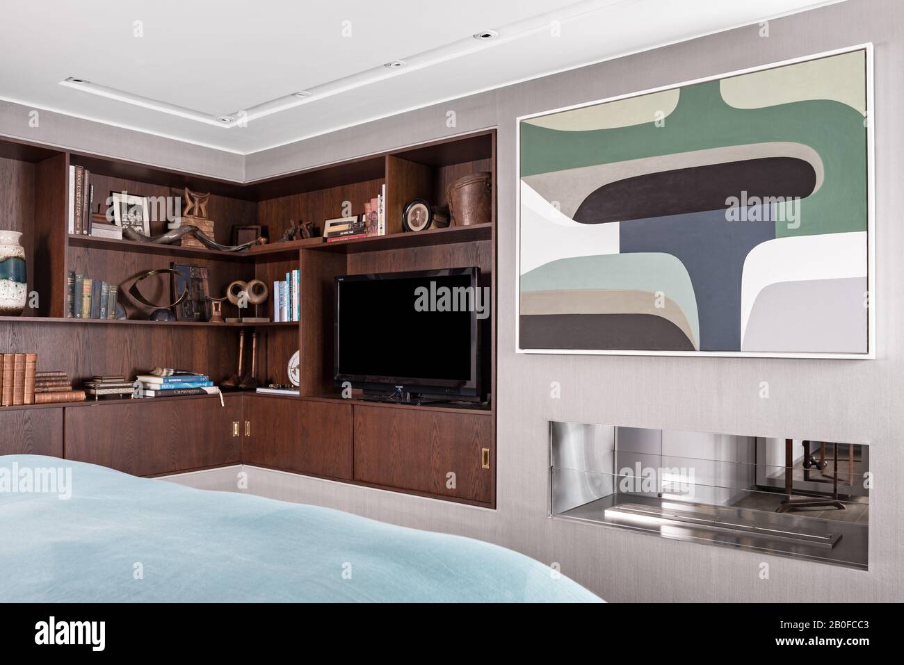 TV su scaffalature rivestite in legno e grandi opere d'arte nella camera da letto del moderno appartamento West London. Foto Stock