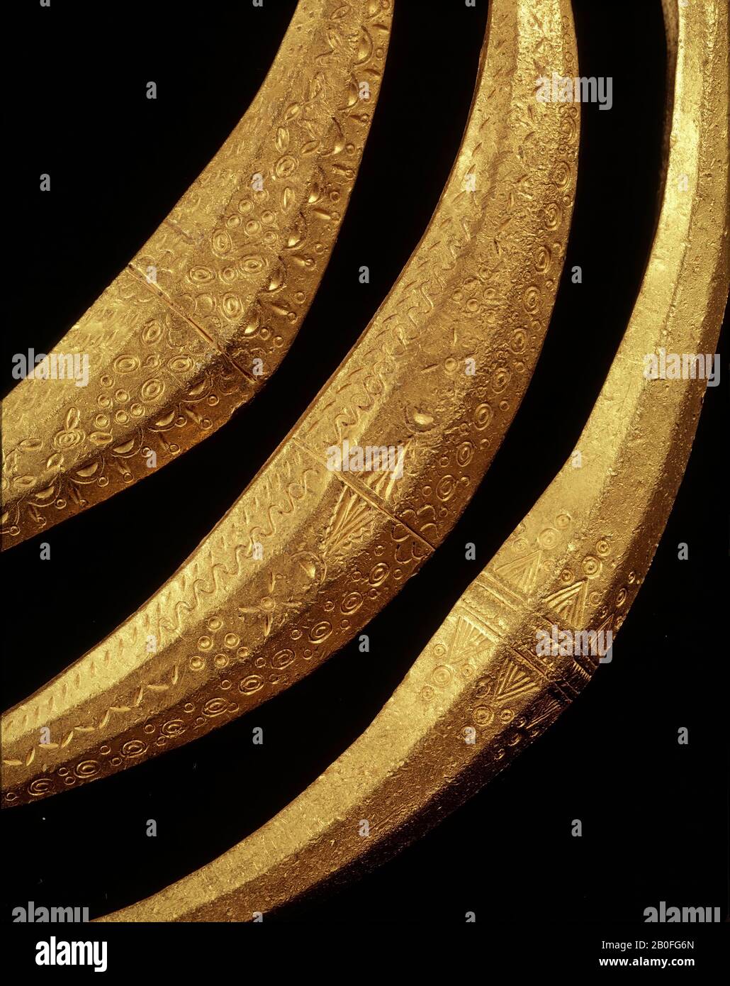Anello a collo frontale in oro massiccio, realizzato con solidi romani fusi. L'estremità allargata ha un diametro esagonale. In realtà, solo il fronte ha tre sfaccettature, il retro è piatto. La parte allargata si estende su entrambi i lati in un filo tondo, una cui estremità è dotata di un occhio a pera, l'altra di un bottone, che cattura l'occhio. La parte allargata è decorata con un ornamento timbro di vari motivi semplici., anello del collo, metallo, oro, 16,1 x 14 cm, vmea 400-400, Paesi Bassi, Overijssel, Olst-Wijhe, Olst Foto Stock
