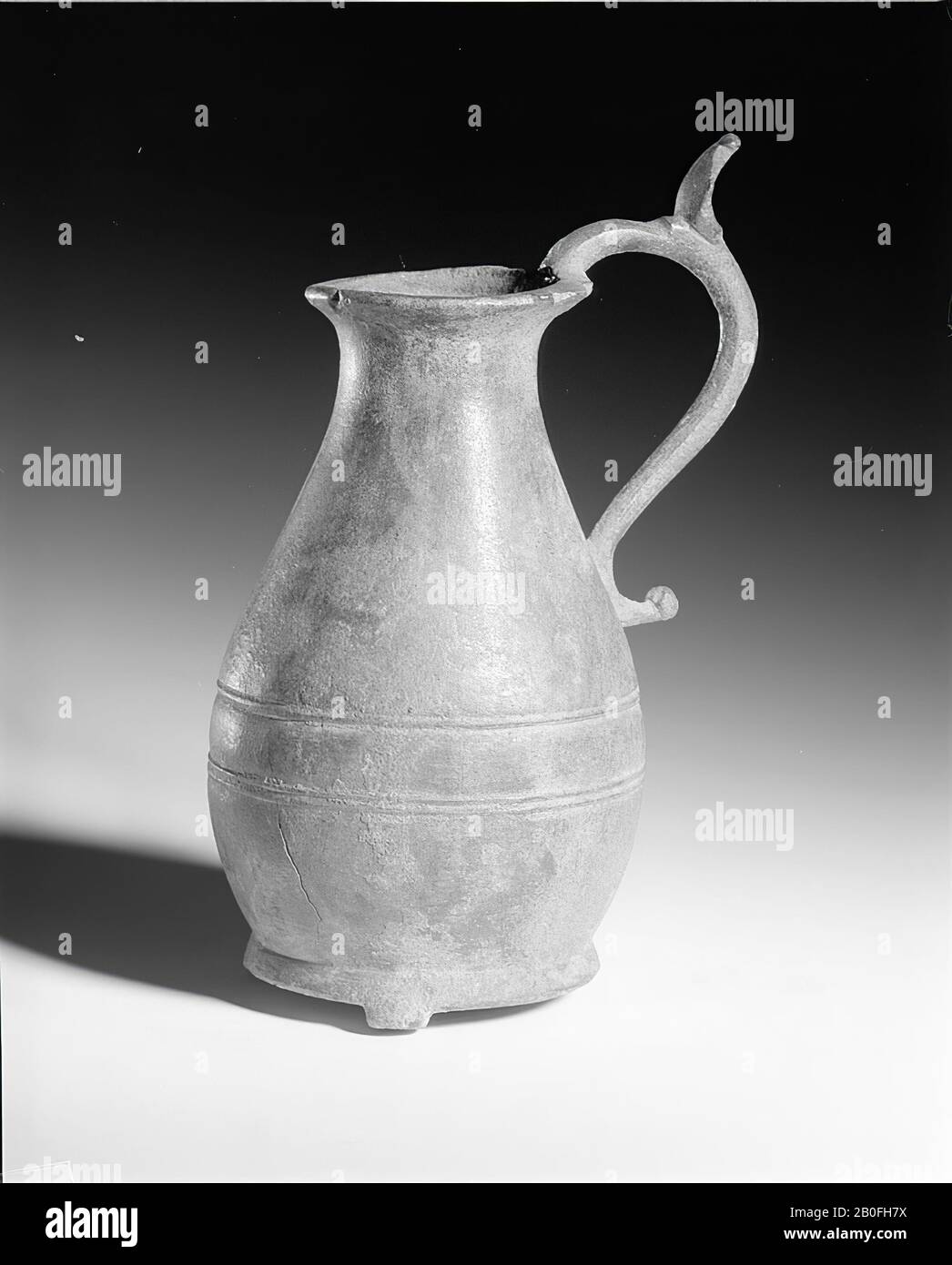 Caraffa in bronzo Frankish. Il fondo convesso ha tre piccole gambe. Sull'orecchio curvo a forma di S un labbro verticale per premere contro il pollice durante il versamento., Lattina, metallo, bronzo, altezza: 19,3 cm, vmeb 600-700 ad, Olanda, Gelderland, Wijchen, Wijchen Foto Stock