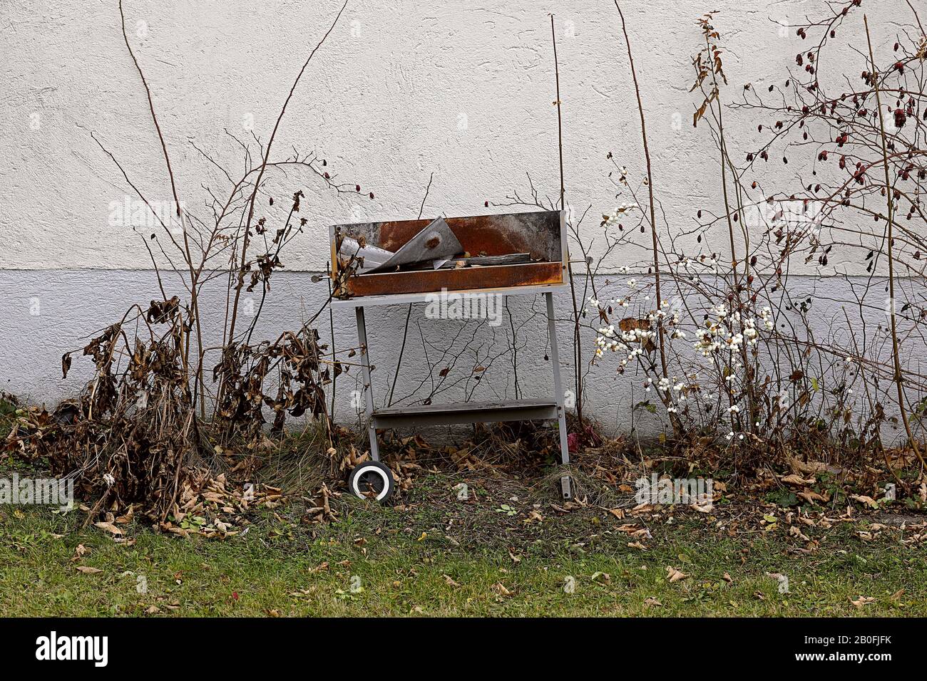 Griglia rotta sulla parete della casa tra la macchia asciutta e l'erba Foto Stock