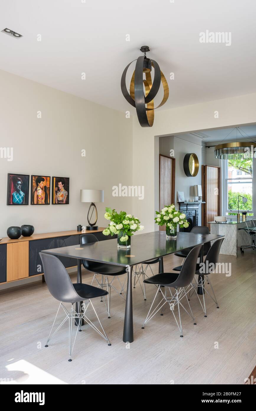 Lampada a sospensione classica in sezioni di ottone e bronzo sopra il tavolo da pranzo in rovere tinto ebano su gambe in bronzo con sponda Molteni Foto Stock
