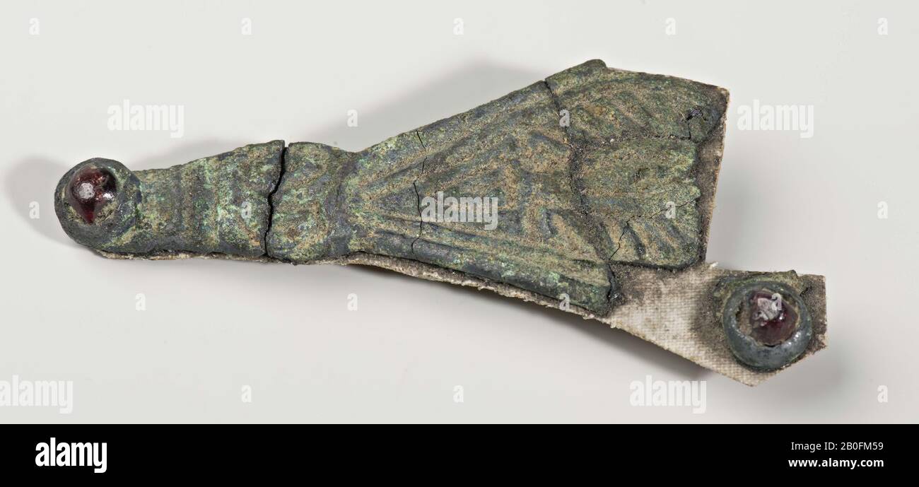 Un frammento di una pedana. La pedana era originariamente a forma di diamante con un roundel con un almandine nei suoi punti più ampi. Una testa di animale con un almandine sul naso forma l'estremità del piede., fibula, frammento di fibula curvo (pedana), metallo, bronzo, almandine, 5,9 x 2,6 cm, 5 grammi, vmeb 530-600, Paesi Bassi, Limburg, Roermond, Swalmen Foto Stock