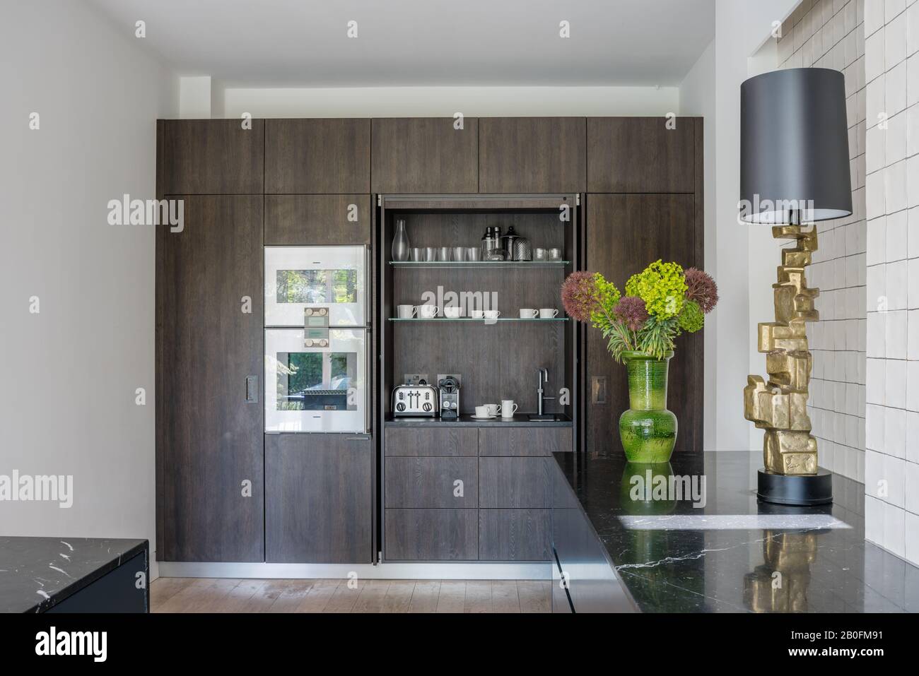 Armadietti in noce Clare Turner per la prima colazione, tè e caffè con lavandino e rubinetto per acqua calda Quooker, lampada Bloc in ottone fuso dal design CTO. Foto Stock