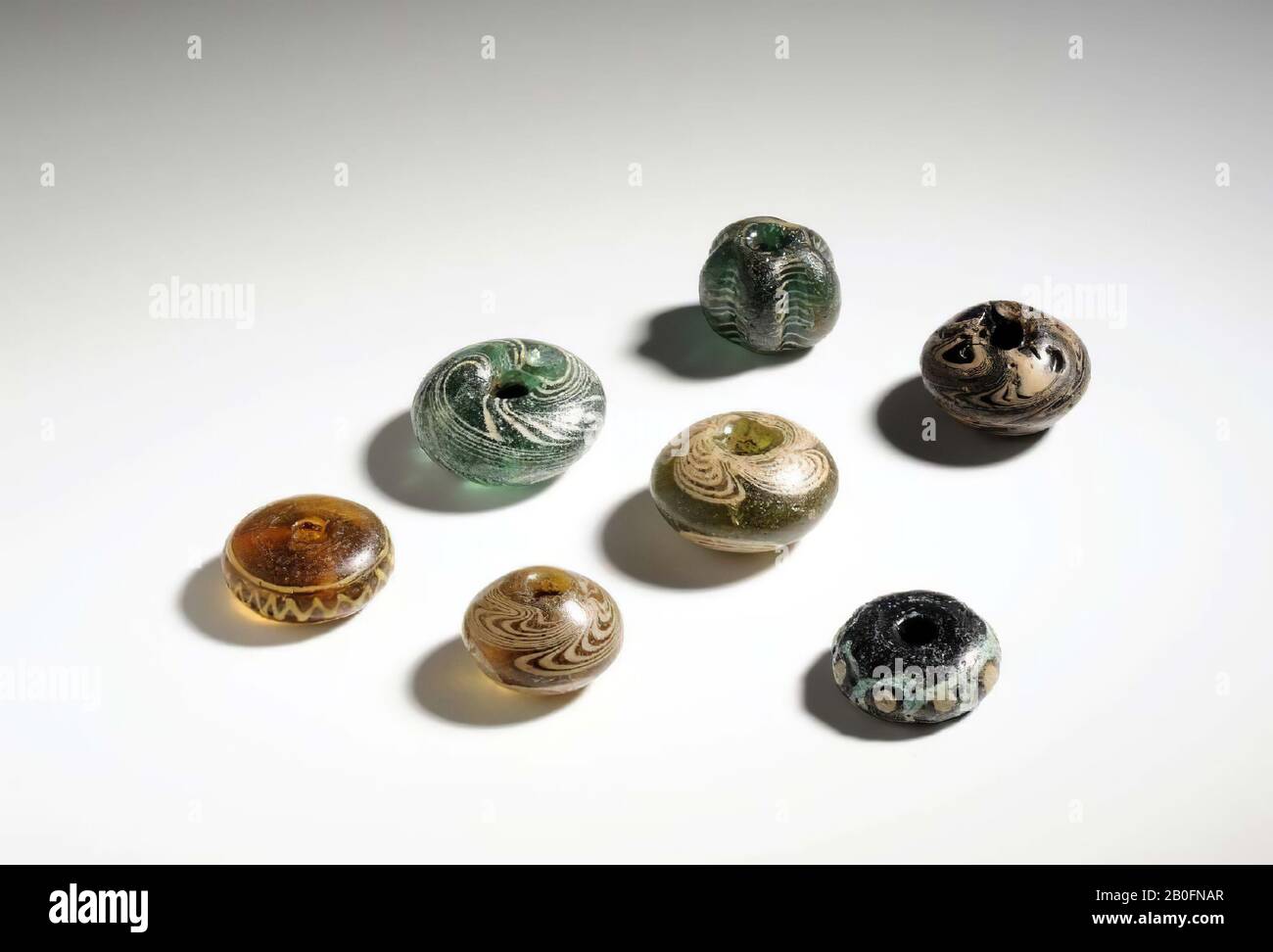 Cordone anulare di vetro verde traslucido con decorazione a filo bianco attorno alle aperture del foro, a quattro lati, vorticoso ai lati. Prendi. RH 397 C., tallone, goccia di inchiostro, vetro, altezza: 2,3 cm, vmeb 550-650, Paesi Bassi, Utrecht, Rhenen, Rhenen, tomba 402 Foto Stock