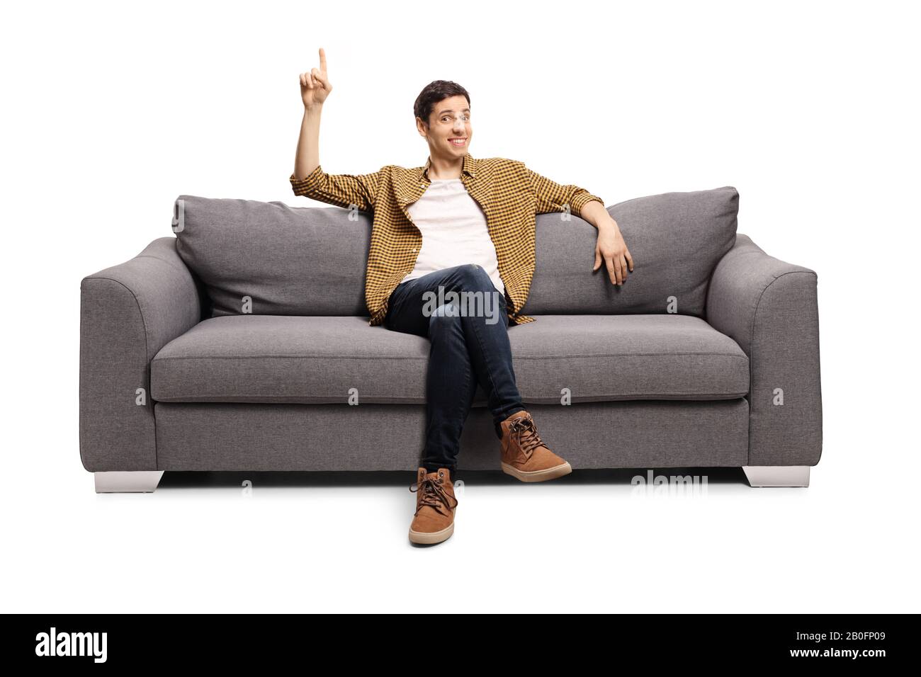 Giovane uomo seduto su un divano e rivolto verso l'alto isolato su sfondo bianco Foto Stock