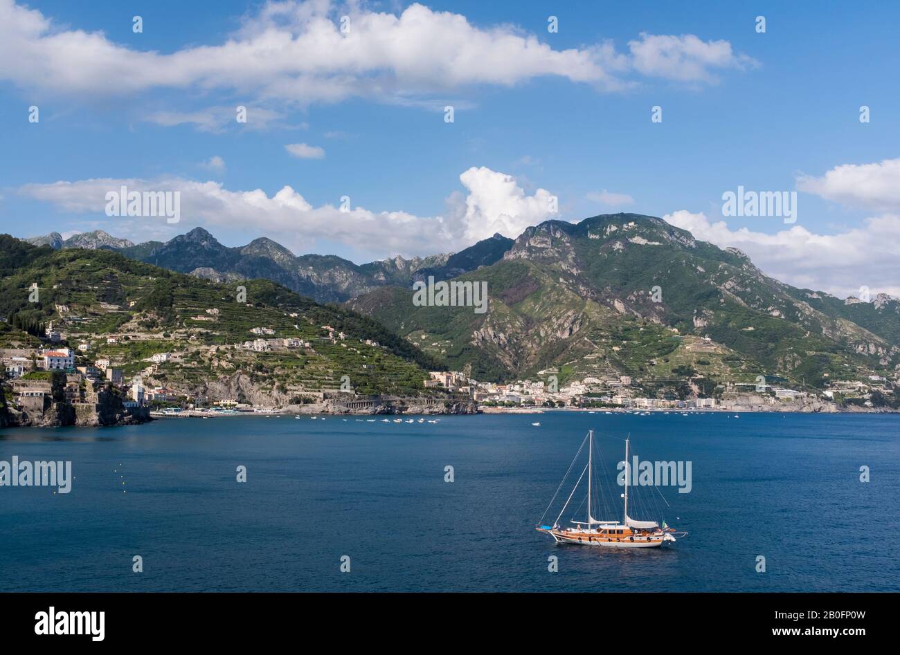 Uno yacht ancorato al largo della costiera amalfitana in una luminosa giornata estiva in Italia, con il paesaggio montano al di là. Foto Stock