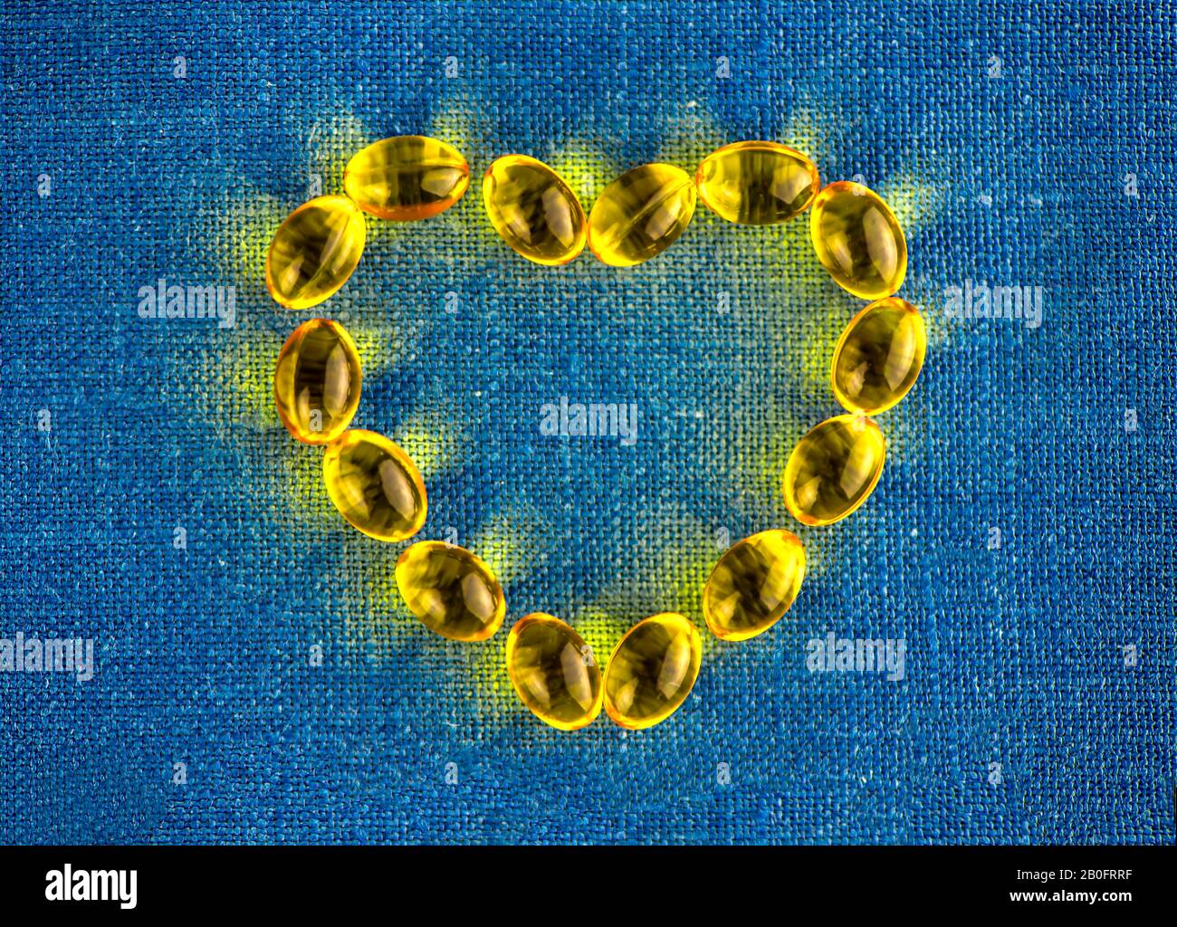 Giallo capsule di gelatina a forma di cuore. copia spazio. vitamine D, omega 3, E. SALUTE Foto Stock