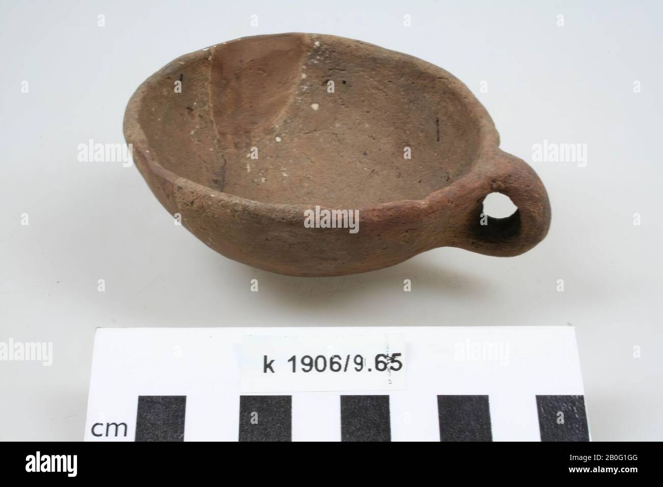 Vassoio marrone liscio con un orecchio di terracotta. Vecchi incollaggi e aggiunte., Bijpot, ceramica, h: 4 cm, diam: 9 cm, br (incl Orecchio): 11 cm, preistoria -800 Foto Stock