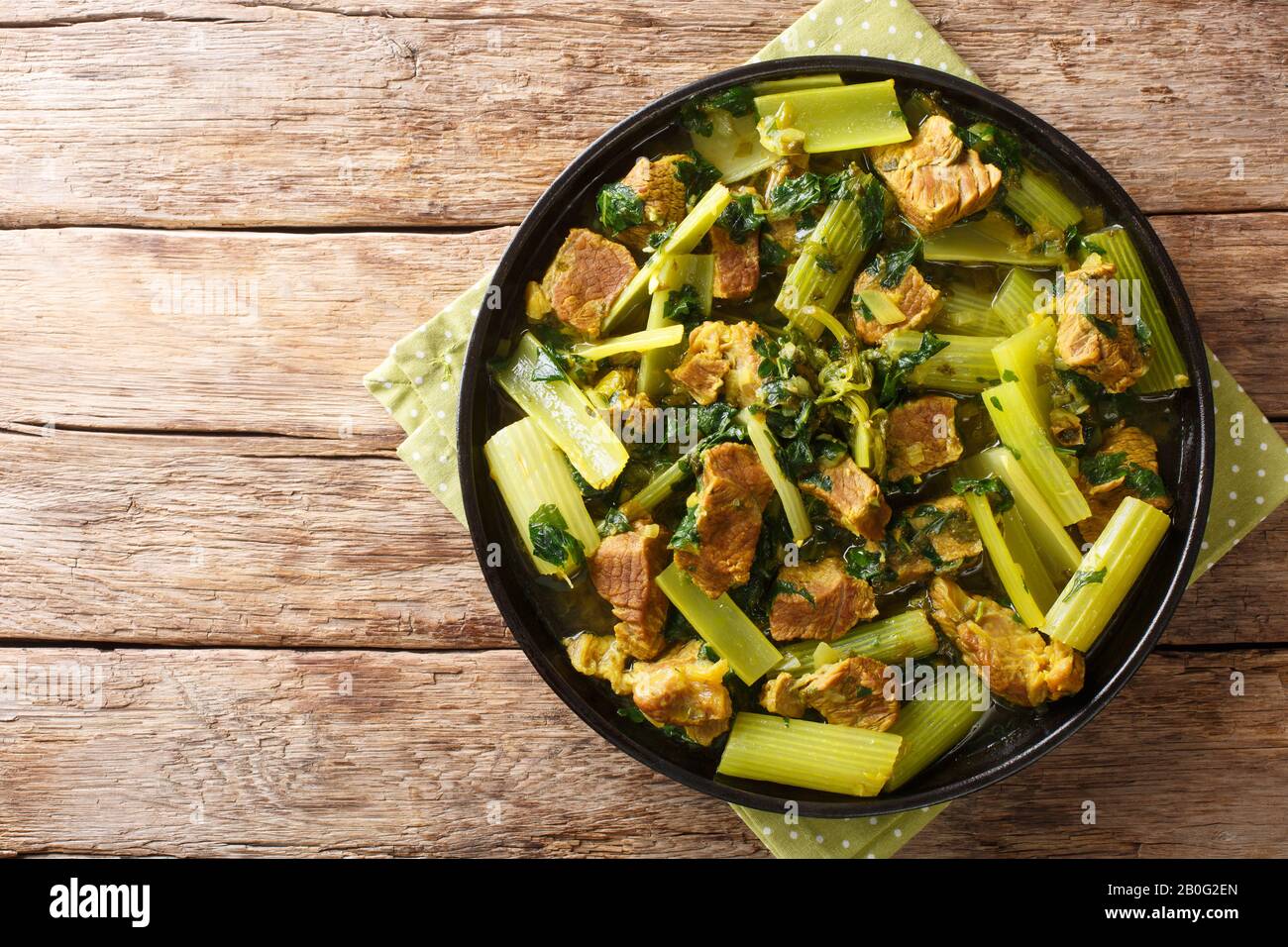 porzione di sedano stufato con manzo, cipolle, menta e prezzemolo in un piatto sul tavolo. Vista dall'alto orizzontale Foto Stock