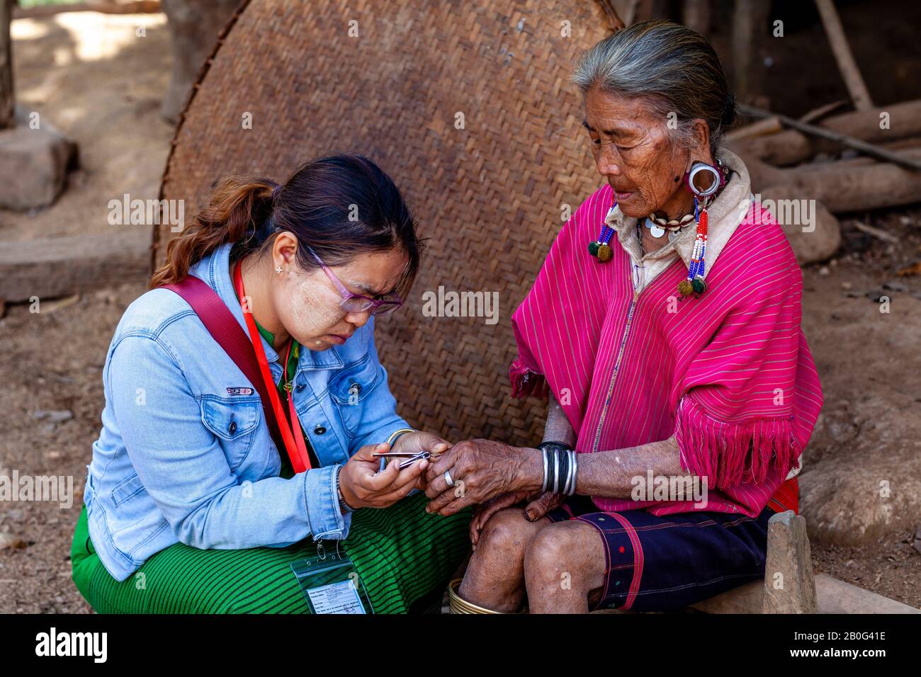 Una Guida Turistica Taglia Le Unghie Delle Dita Di Una Donna Anziana Dal Gruppo Etnico Di Kayaw, Villaggio Di Htay Kho, Loikaw, Myanmar. Foto Stock