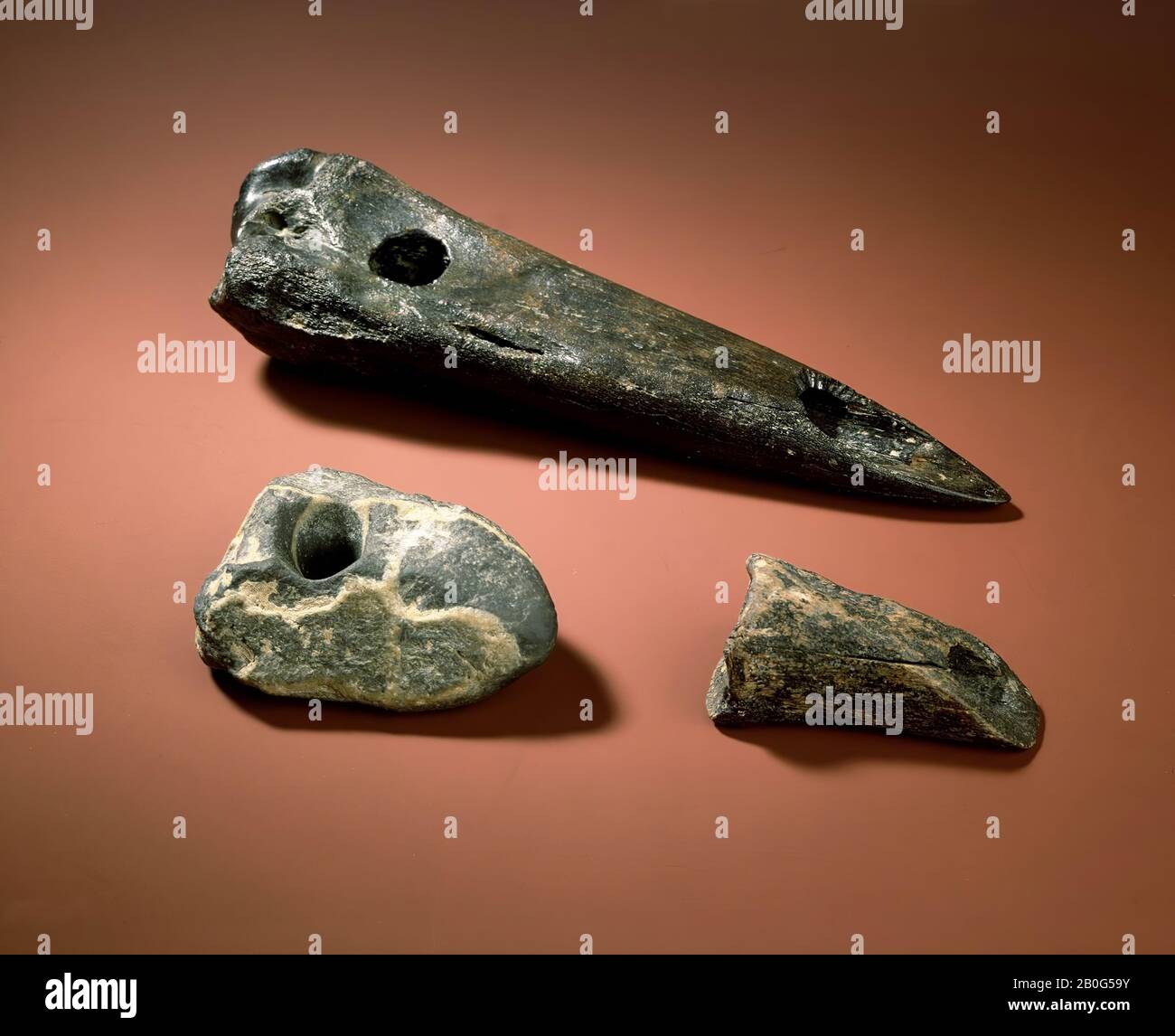 pietra di quarzite grigio-blu con movimenti di quarzo bianco. Forma leggermente allungata con un'estremità piatta e un'estremità appuntita, che sembra essere stata levigata. Approssimativamente nel centro di gravità della pietra un foro a doppio cono (diametro esterno 3,6 cm, diametro interno 1,7 cm), eseguito in tecnica di urto o foratura e levigato nella parte più stretta. Anche se la pietra avrebbe potuto naturalmente essere netta indebolimento, c'è la possibilità che egli appartiene alle gambe della Brown Bank ed è legato alle ben note pietre rotonde con clessidra-piercing, pietra, pietra, 11,6 x 8,9 cm Foto Stock