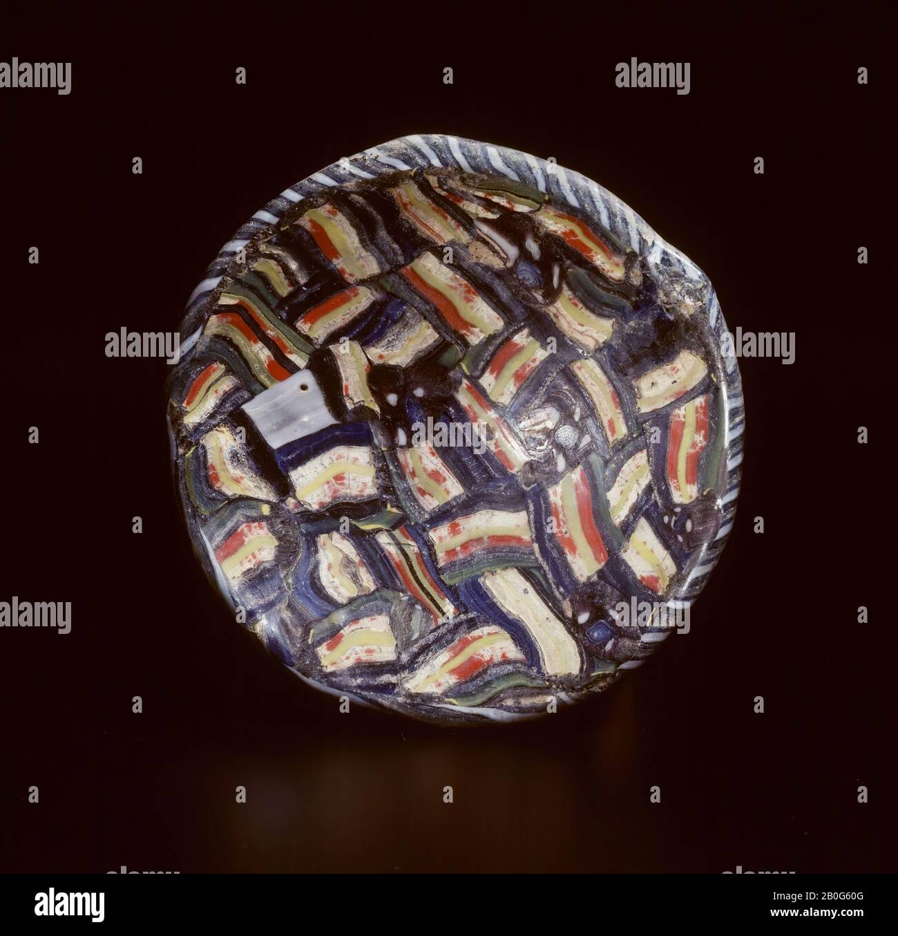 Piccola ciotola di vetro a blocchi-millefiori. Vetro stampato. Le barre di vetro utilizzate sono realizzate in diverse tonalità di verde, rosso, bianco e blu. Il bordo è fatto di un filo di vetro intrecciato di vetro bianco, blu e verde ed è regolato separatamente. Il piatto è lucidato solo all'interno, levigato solo all'esterno e quindi rimasto opaco., beffa, piatto, vetro, diam. 7,7 cm, Roman 1-100 d.C., Paesi Bassi, Gelderland, Nijmegen, Nijmegen Foto Stock