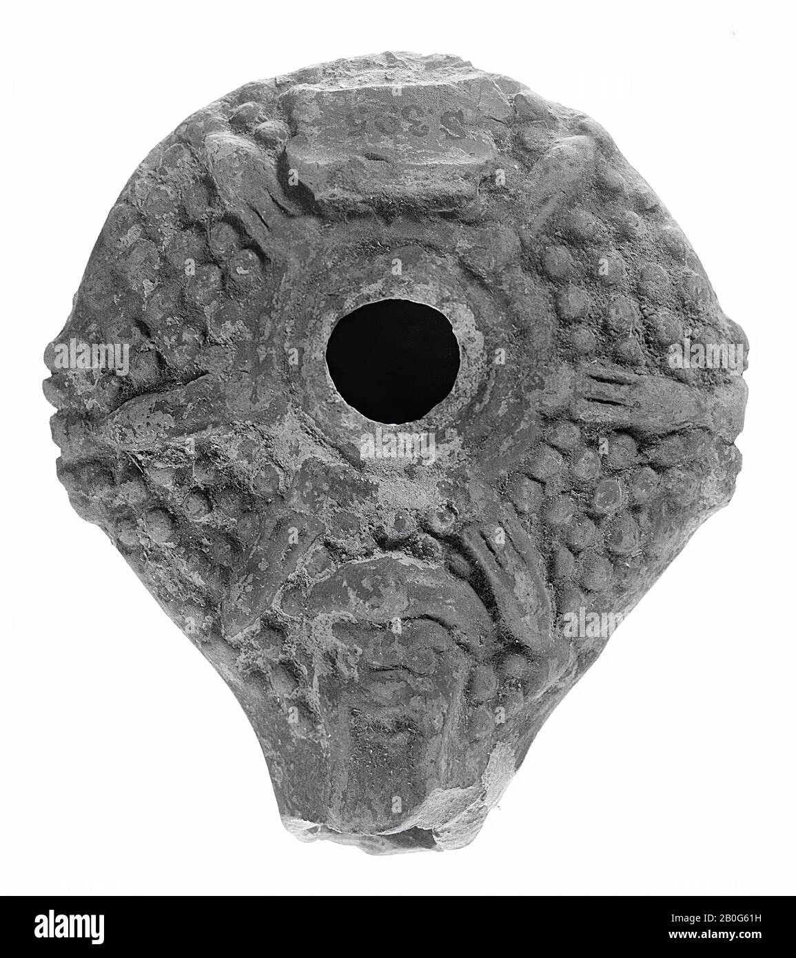 Lampada ad olio verniciato rosso con corpo rotondo su uno strato di piedistallo. Il piccolo foro di riempimento è circondato da un bordo di scarico. La spalla è decorata con fasce in rilievo trasversali, che sono collegate alla fascia in rilievo circolare, con punti di rilievo intermedi. Su entrambi i lati sono presenti due piccole maniglie a coste. Sul beccuccio si trova una maschera, lampada ad olio, terracotta, terracotta, 4,3 x 8,3 x 7,5 cm, 2nd e 1st secolo a.C. 0-1, Asia Foto Stock