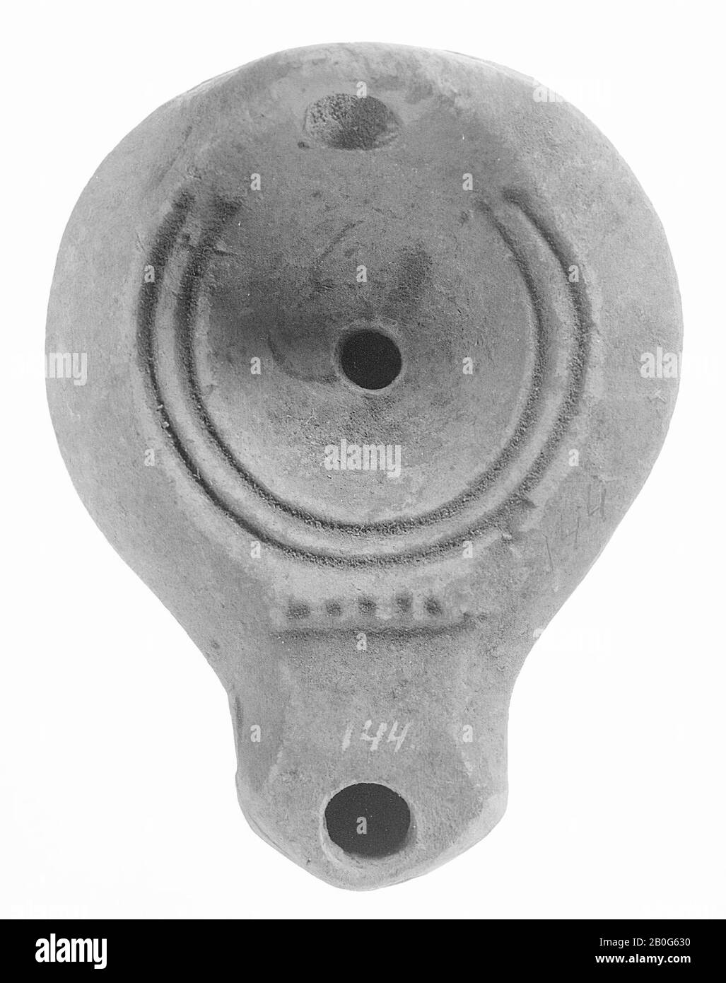 Una lampada ad olio in terracotta gialla con corpo rotondo su base rotonda incassata. Lo specchio cavo è circondato da cerchi concentrici profondi con un piccolo foro di riempimento al centro. Nella parte posteriore è fissata una maniglia forata verticale. L'ampio beccuccio con il piccolo foro di fuoco è chiuso bruscamente e decorato sul bordo dello specchio con una linea orizzontale a cinque punti., lampada ad olio, terracotta, terracotta, 4,5 x 9 x 7,5 cm, 1st secolo a.C. -100 Foto Stock