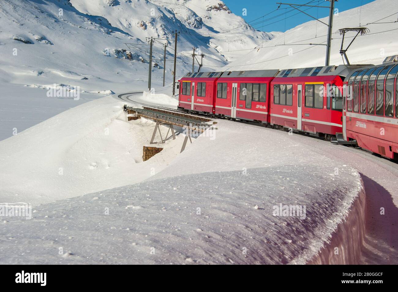 Bernina treno rosso che corre nella neve nelle alpi svizzere in inverno Foto Stock