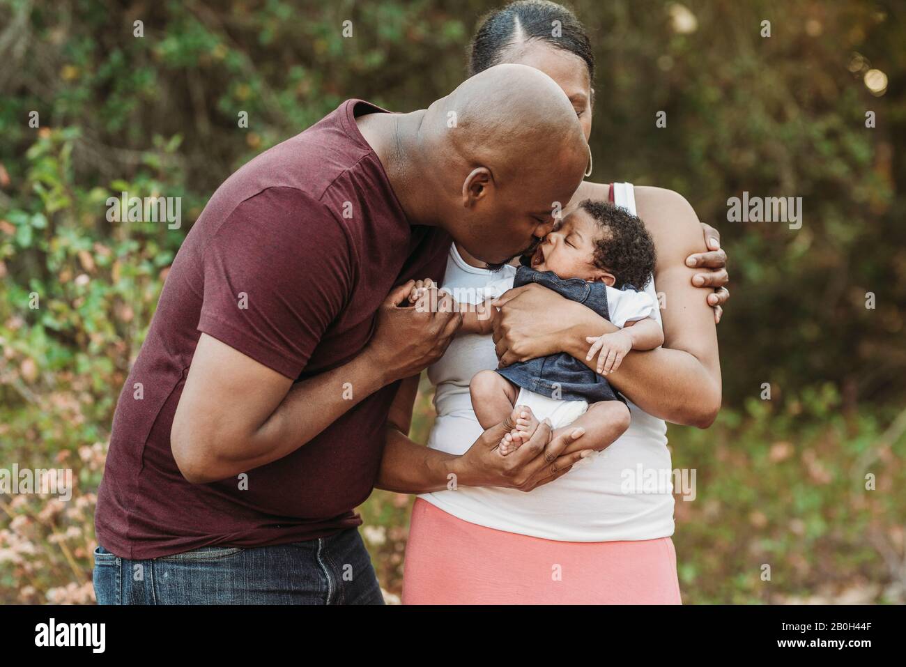 Primo piano felice madre e padre baciare neonato ragazza Foto Stock