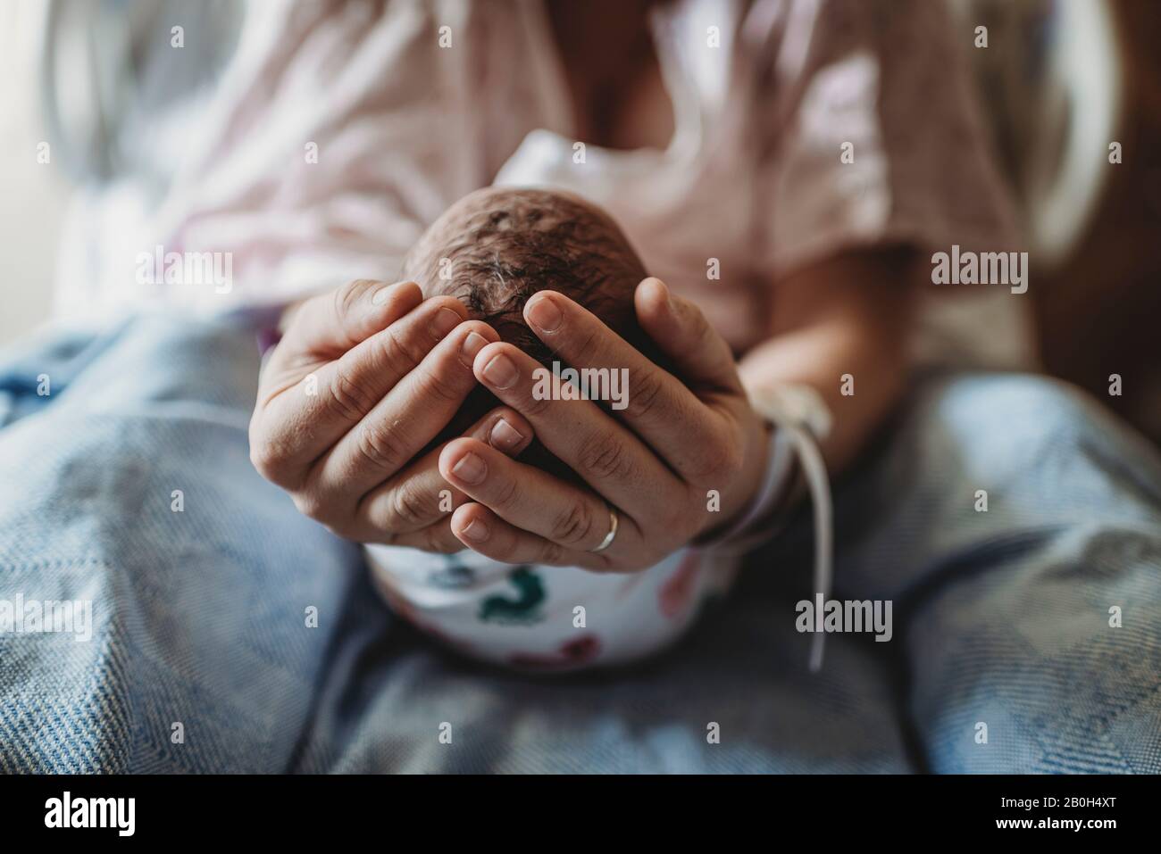 Macro vista delle mani madri che tengono la testa del neonato Foto Stock