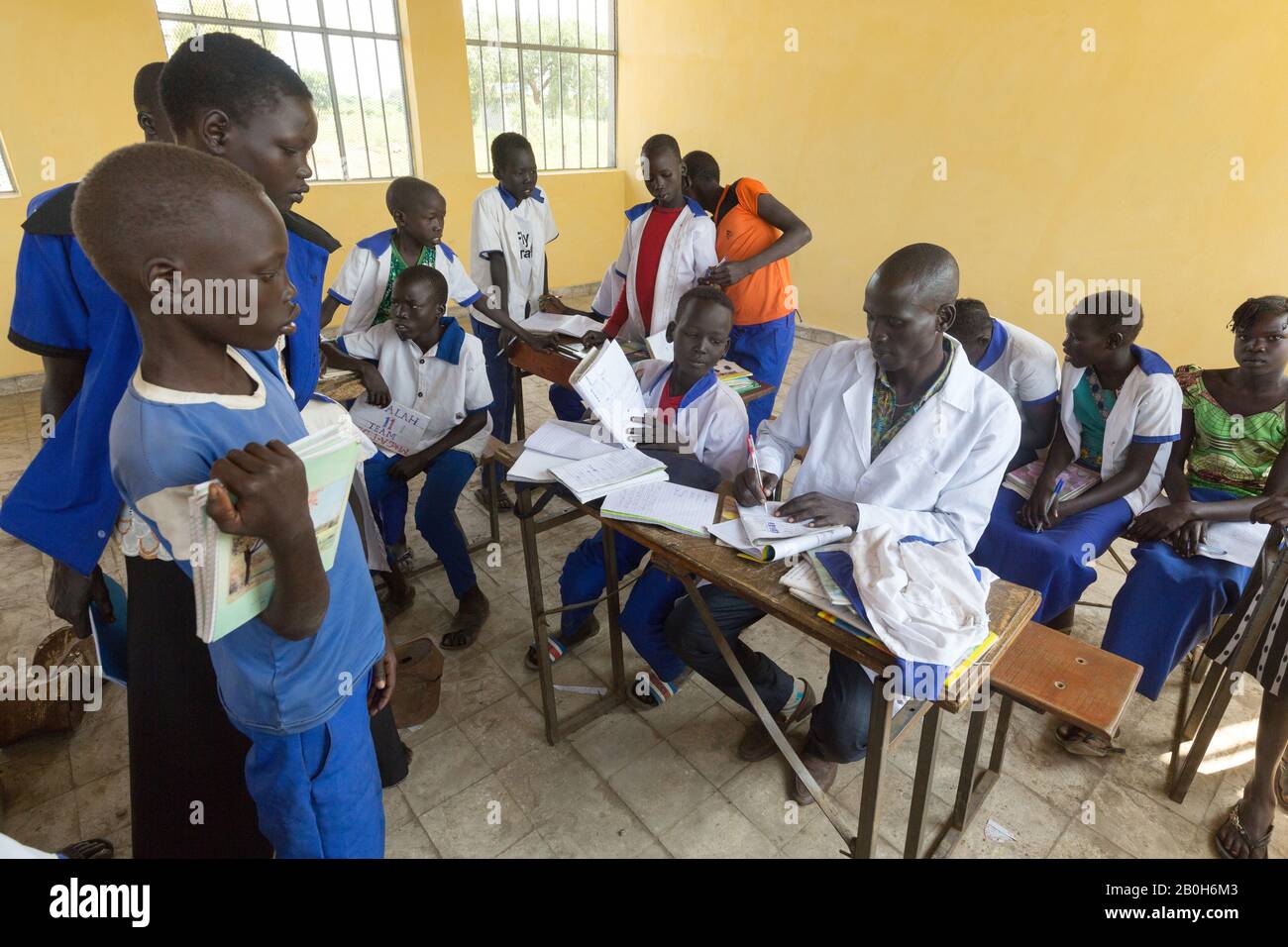 31.10.2019, Belinkum, Gambela, Etiopia - Studenti in uniformi scolastiche che frequentano corsi di scuola elementare. Un insegnante che controlla i notebook tra le sue tacchini Foto Stock