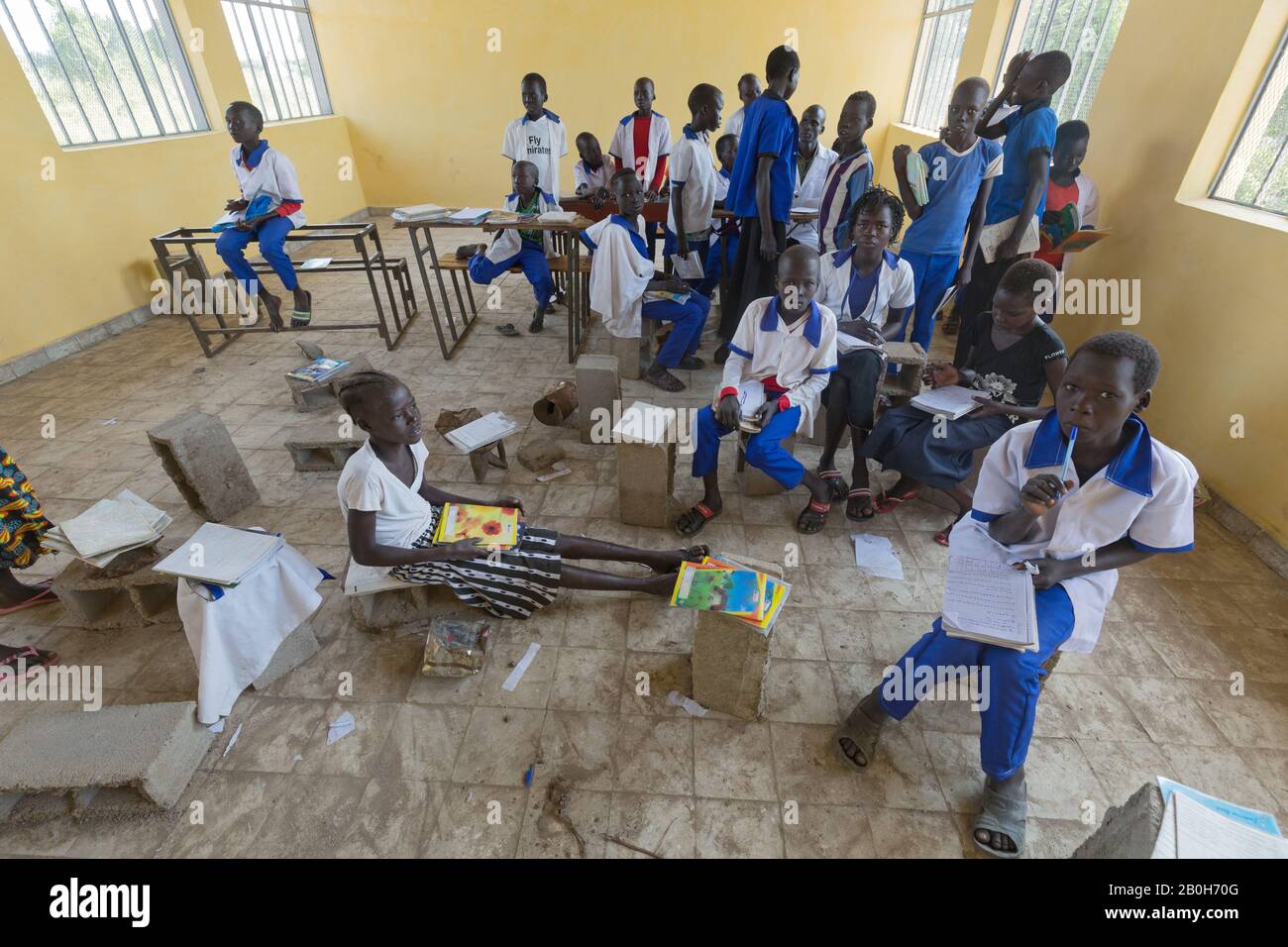 31.10.2019, Belinkum, Gambela, Etiopia - Studenti in uniformi scolastiche che frequentano corsi di scuola elementare. Un insegnante che controlla i notebook tra le sue tacchini Foto Stock