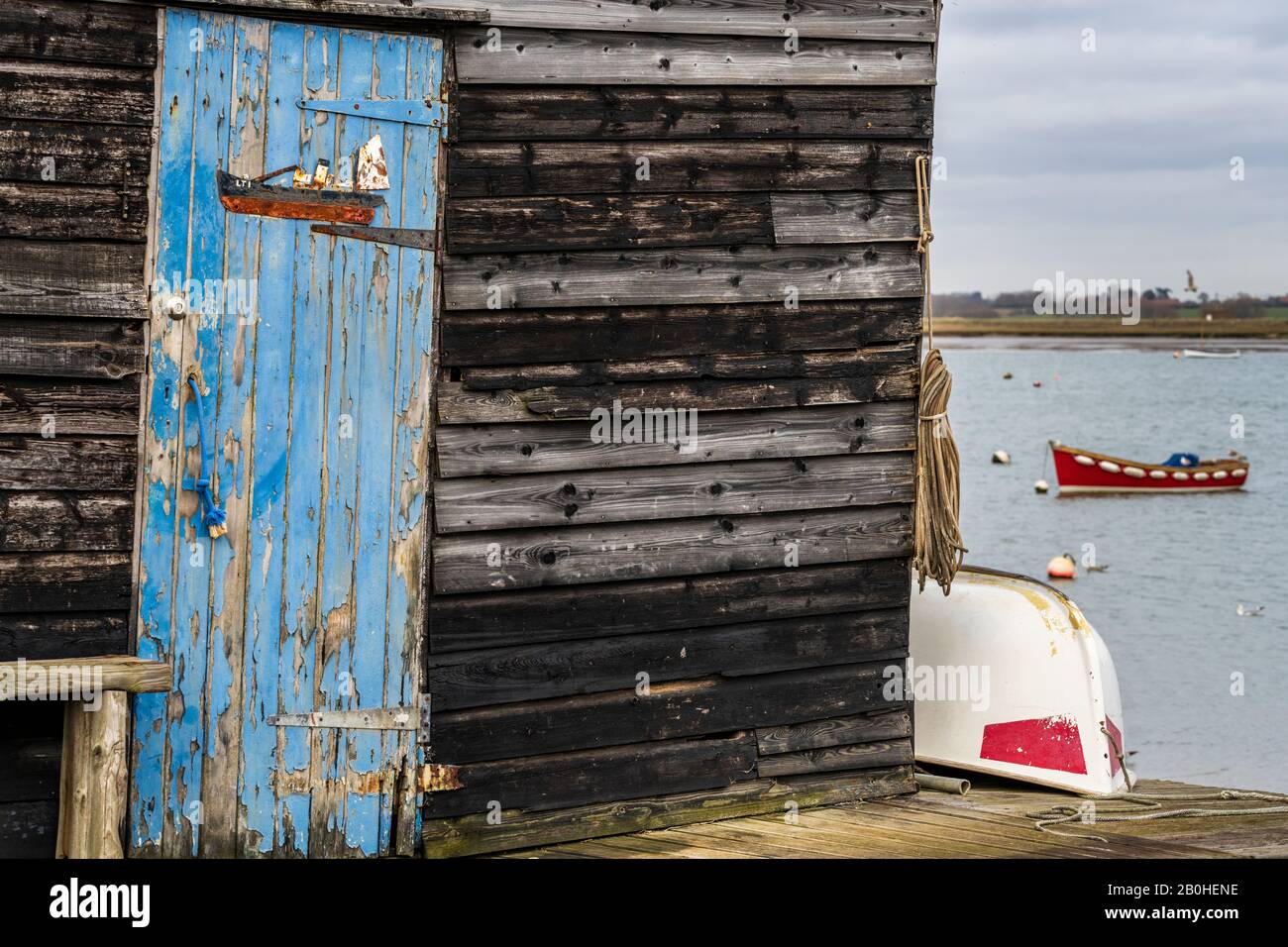 Vecchie capanne di pescatori a Felixstowe Ferry, un piccolo villaggio di pescatori situato a 2 miglia a nord di Felixstowe nel Suffolk. Aringa drifter targa sulla porta. Foto Stock