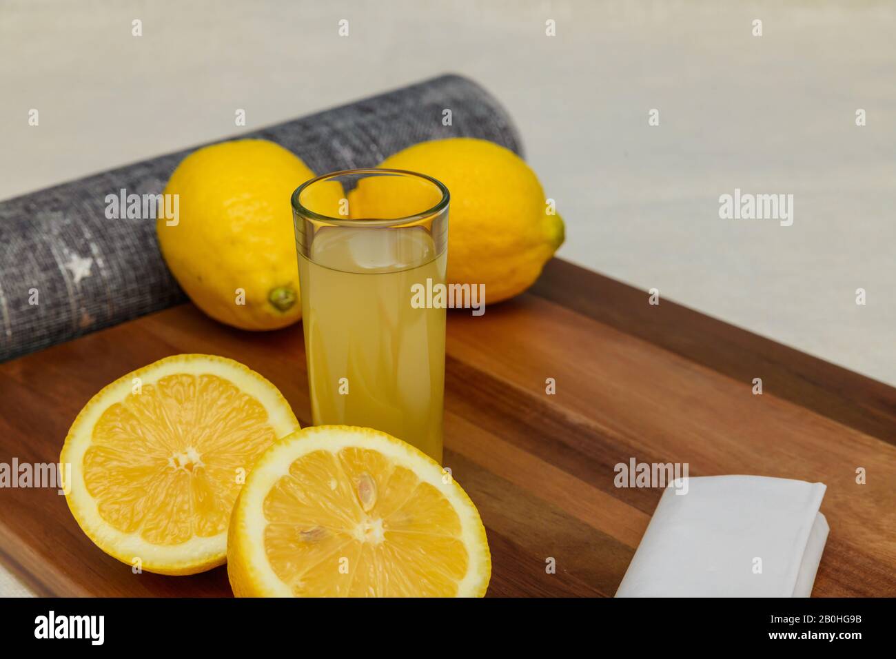 Mattina in cucina con un bicchiere di limone fresco e succo di zenzero con metà limone. Concetto di vita sana, vegano, dieta, detox Foto Stock