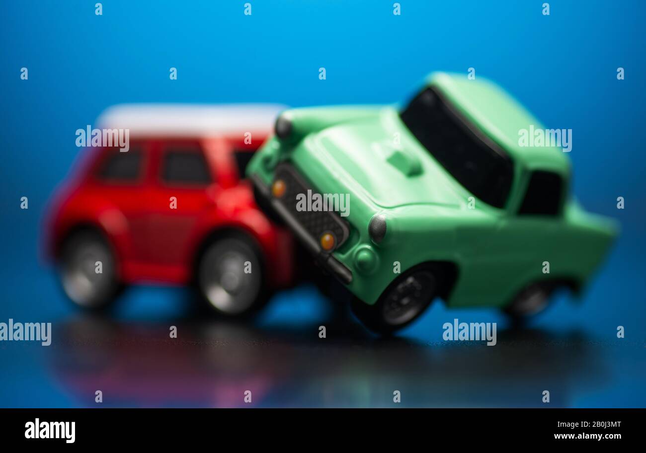 Primo piano colpo di incidente stradale tra un rosso e verde auto giocattolo su un blu dietro. Foto Stock