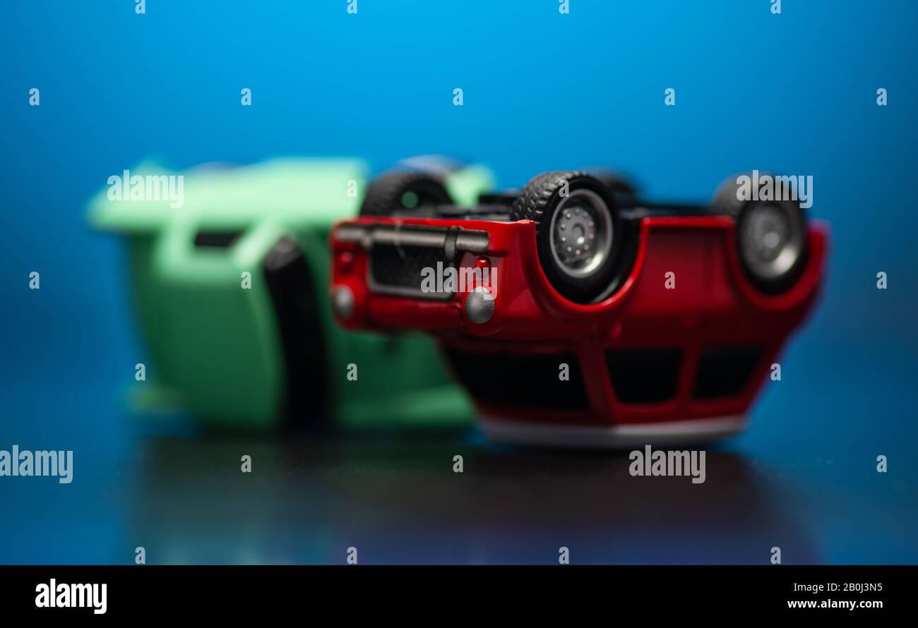 Primo piano colpo di incidente stradale tra un rosso e verde auto giocattolo su un blu dietro. Foto Stock