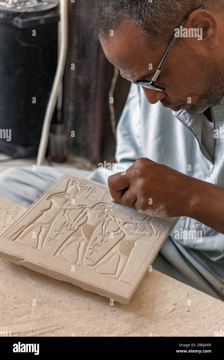 Artigiano locale che intagliano il tradizionale design egiziano antico su una tavoletta di alabastro, vicino a Luxor Foto Stock