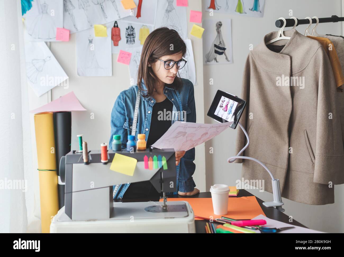 Ritratto di giovane stilista femminile nel suo laboratorio. Giovane ragazza freelancer di successo Foto Stock