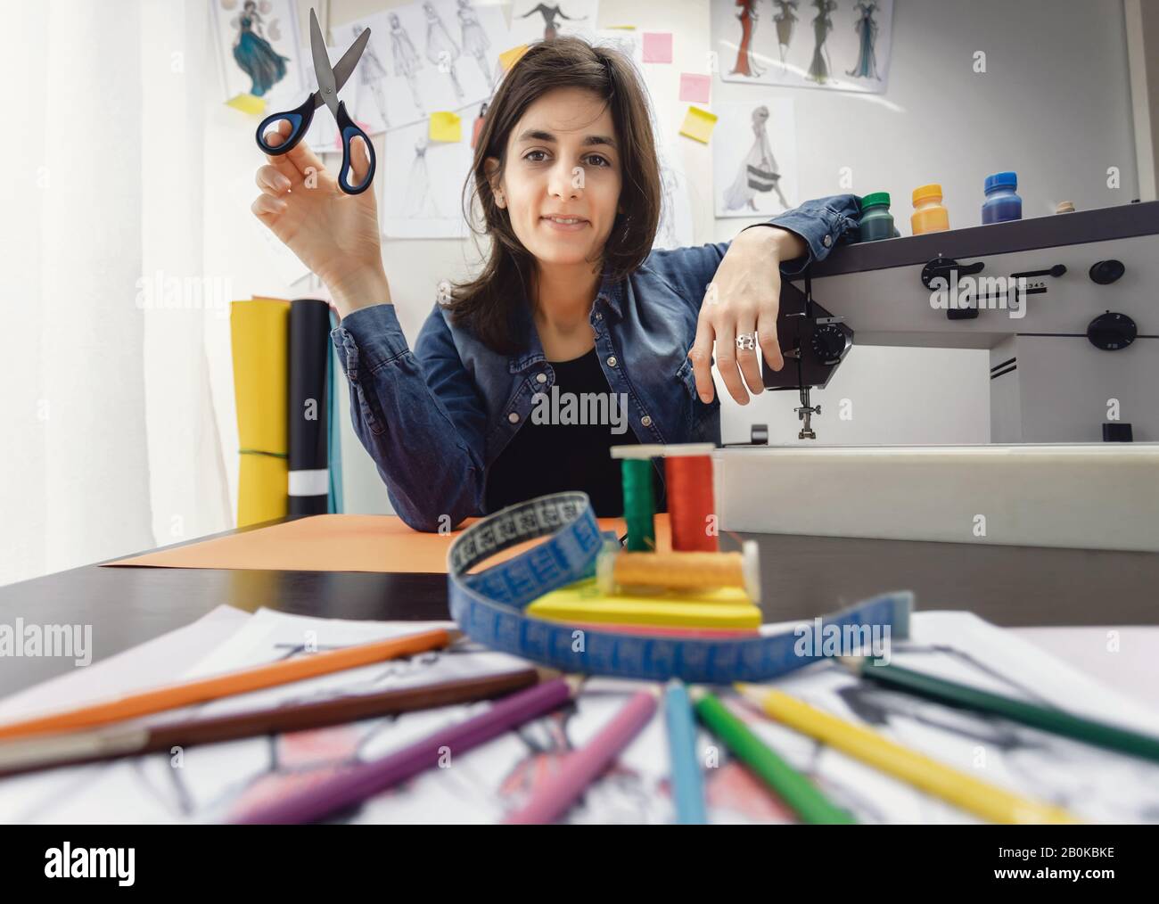 L'attrezzatura su misura misura il nastro, le forbici, il filo e l'ago in officina. Profondità di campo poco profonda sul simbolo del designer di moda. Concetto di moda. Foto Stock