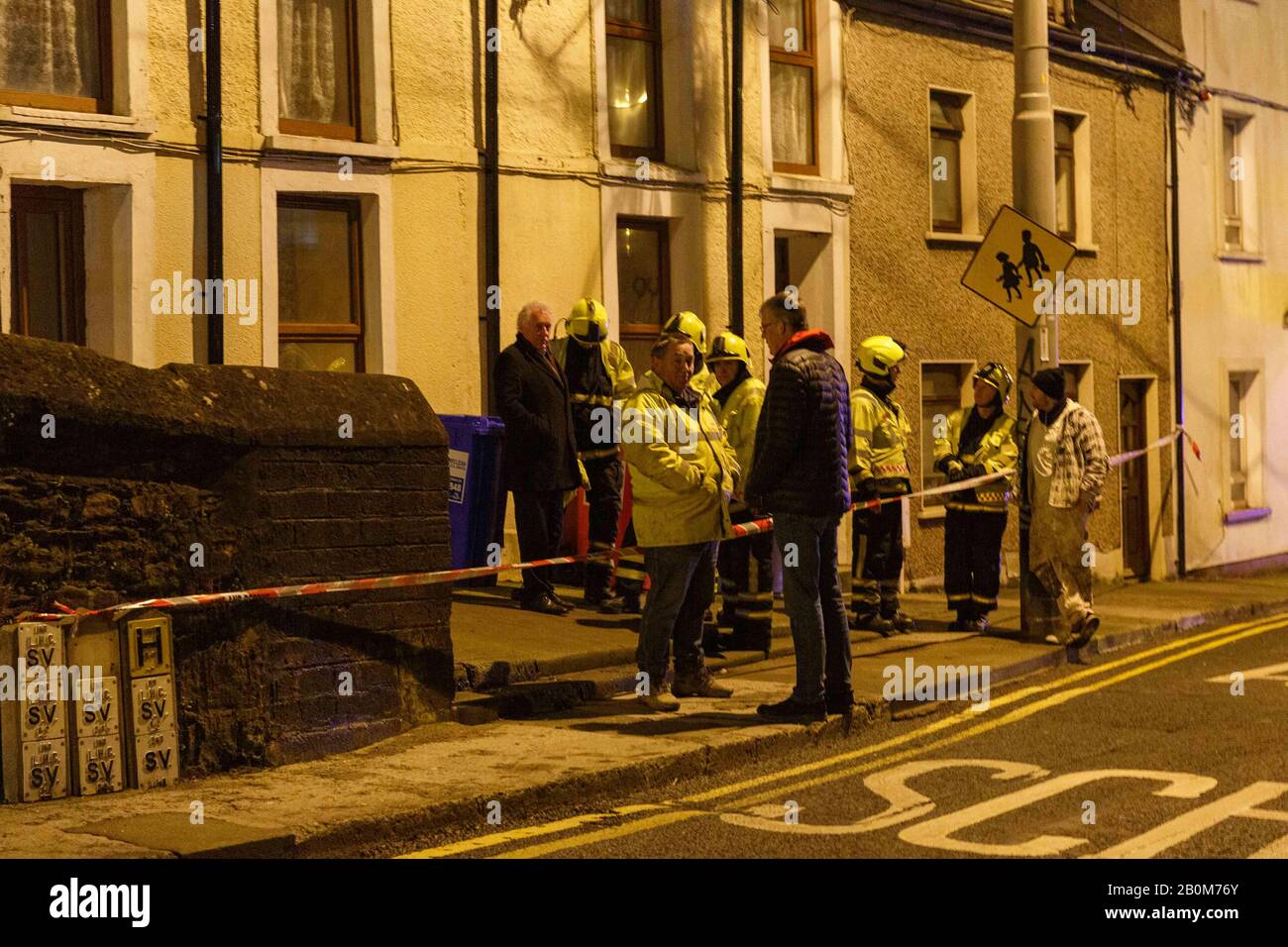 Cork, Irlanda, 20th Febbraio 2020. Case Evacuate Su Roman Street, Cork City. Vigili del fuoco e Residenti che si trovano al di fuori del gruppo inferiore di case colpite dal collasso. Intorno alle 8:30 questa sera la brigata del fuoco della città di Cork è stata chiamata ad un crollo parziale di un muro di confine sulla strada romana. Gli occupanti sono stati evacuati dalle loro case per la loro propria sicurezza, il muro che si pensa di essere oltre 200 anni era crollato nei giardini posteriori di alcune delle case causando danni strutturali ad alcuni. Credito: Damian Coleman/Alamy Live News Foto Stock