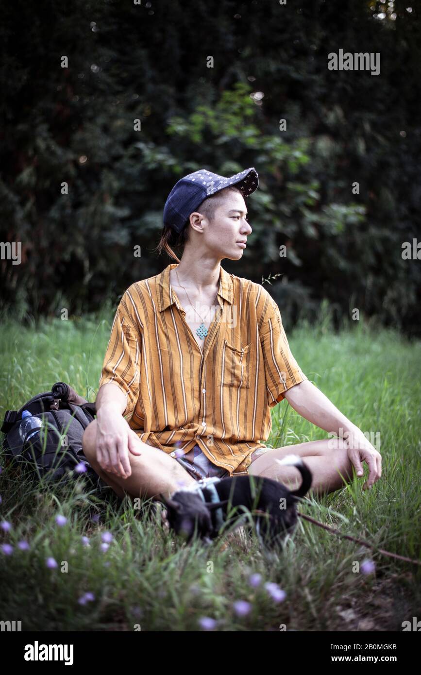 bella persona mista in testa di baseball si siede in erba verde estate Foto Stock