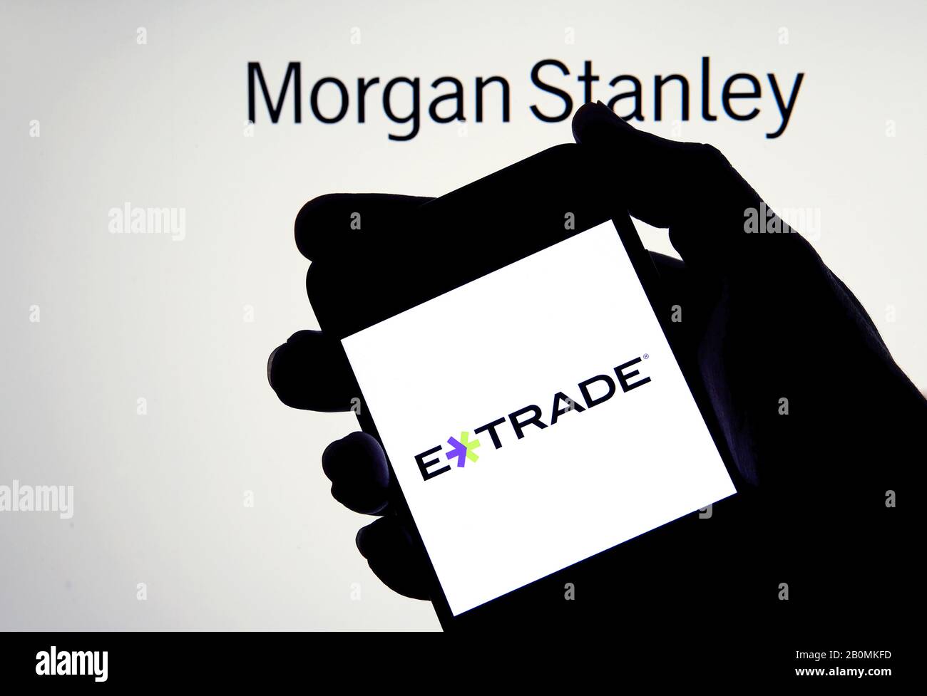 Logo e-trade su uno smartphone in mano con Morgan Stanley sullo sfondo sfocato. Concetto di acquisizione aziendale. Foto reale, non un montaggio. Foto Stock