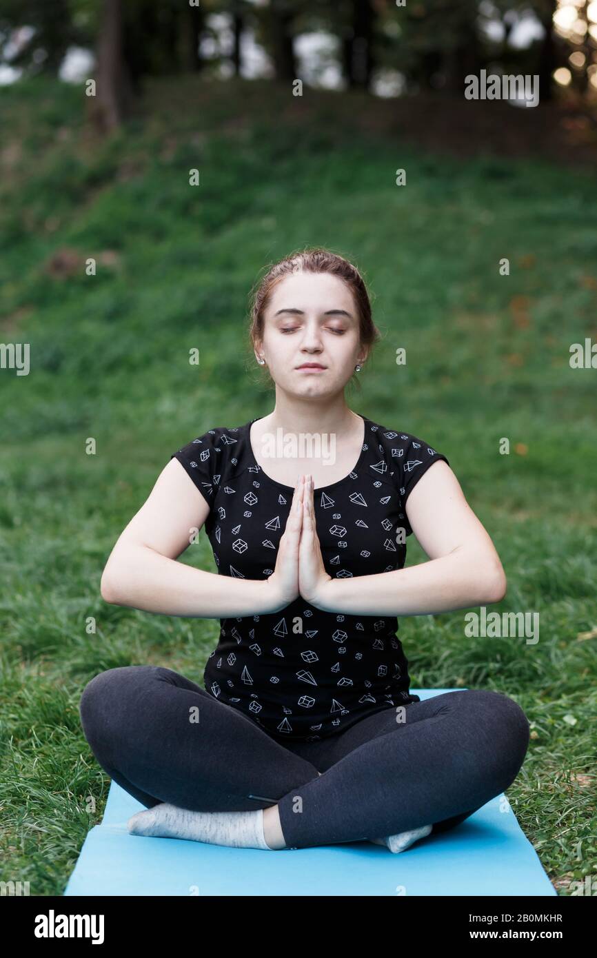 La ragazza rilassata sta facendo yoga nel parco su tappeto Foto Stock