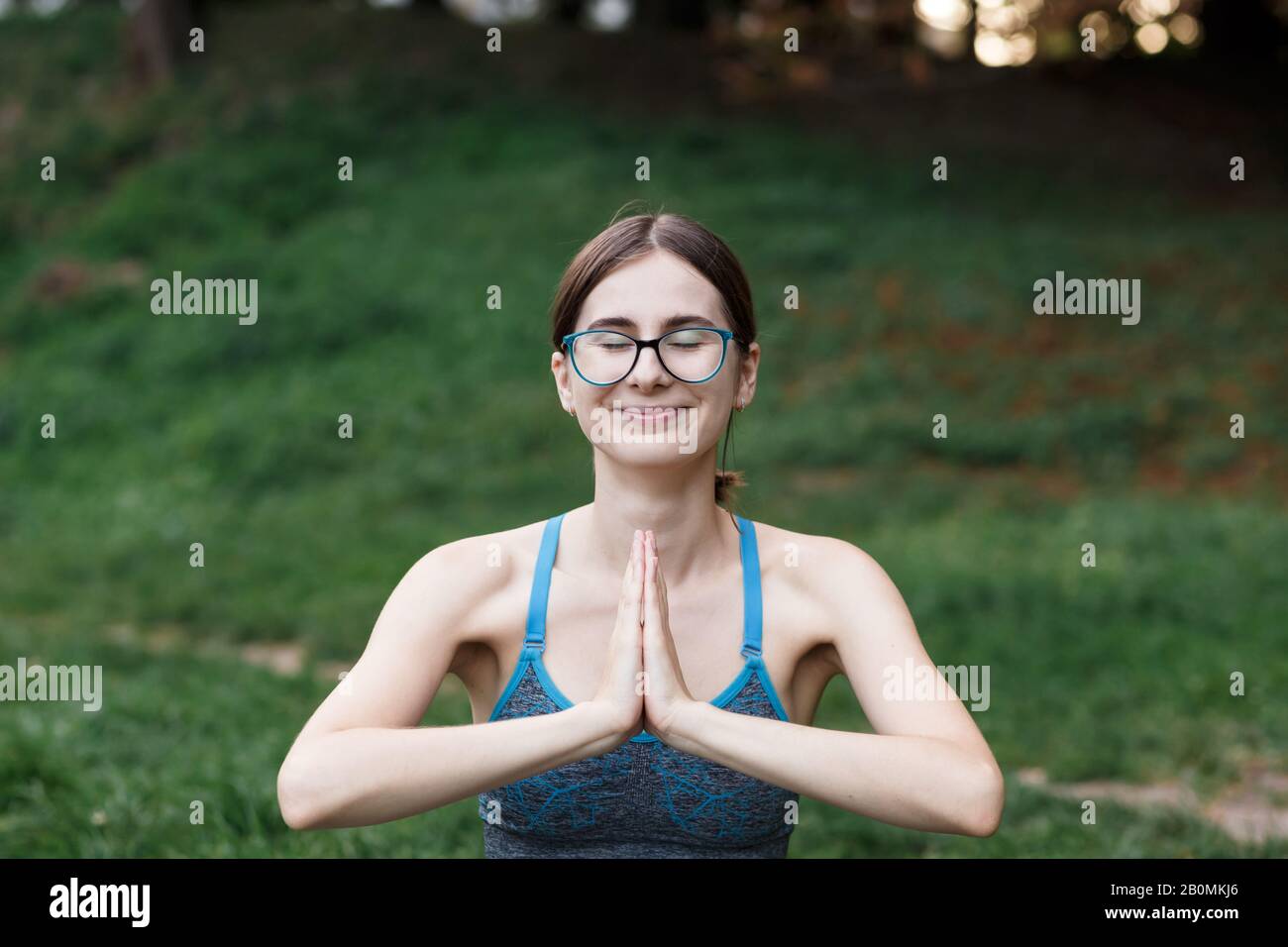 La ragazza rilassata sta facendo yoga nel parco su tappeto Foto Stock