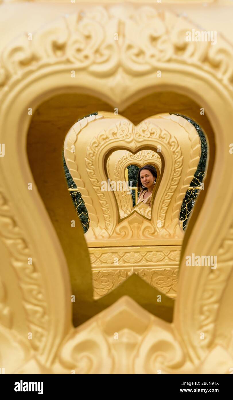 Donna tailandese incorniciata da più cuori d'oro a wat in Pak Nam Pran Foto Stock