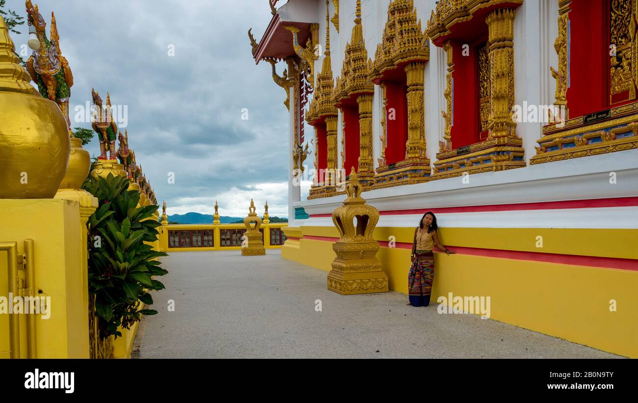 Donna in sarong appoggiata contro la parete di wat in Pak Nam Pran Pranburi Thailandia. Foto Stock