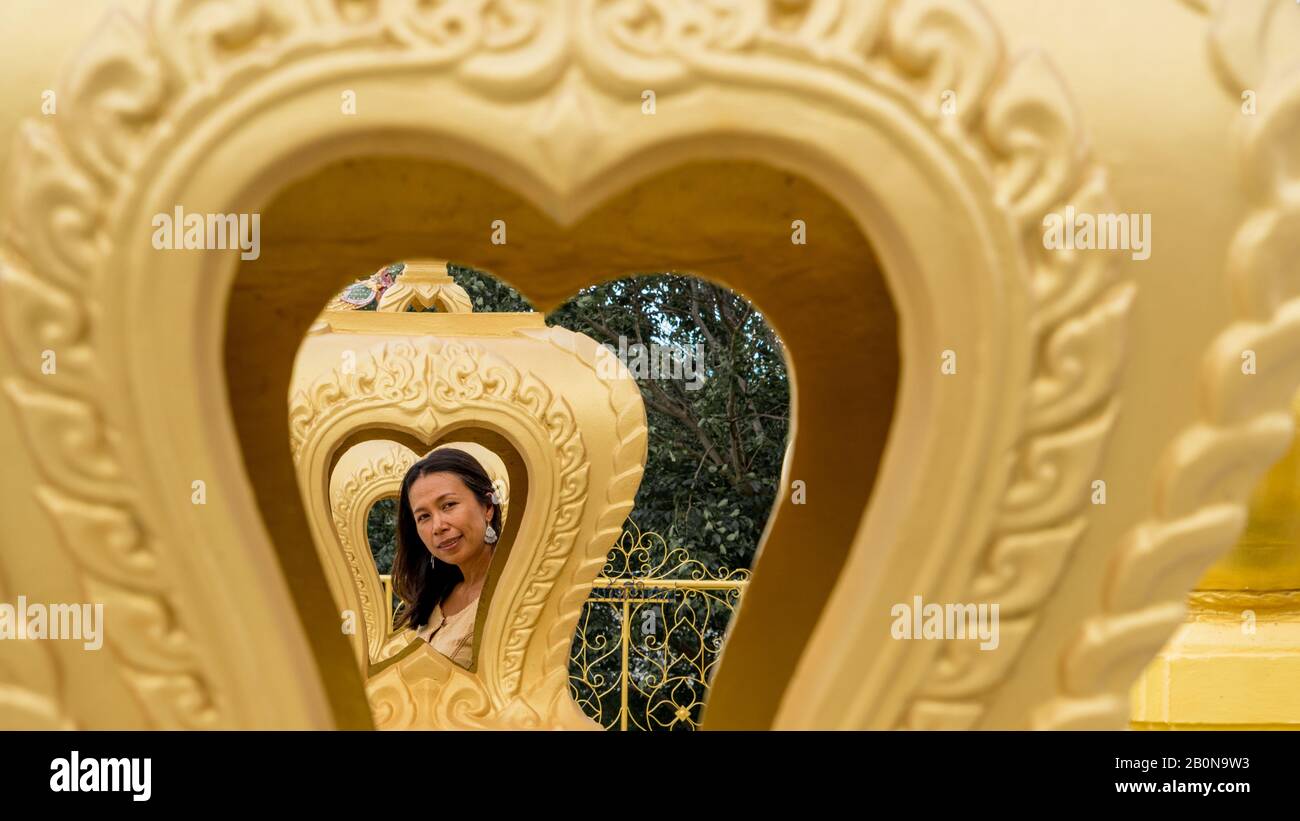 Donna tailandese incorniciata da più cuori d'oro a wat in Pak Nam Pran Foto Stock