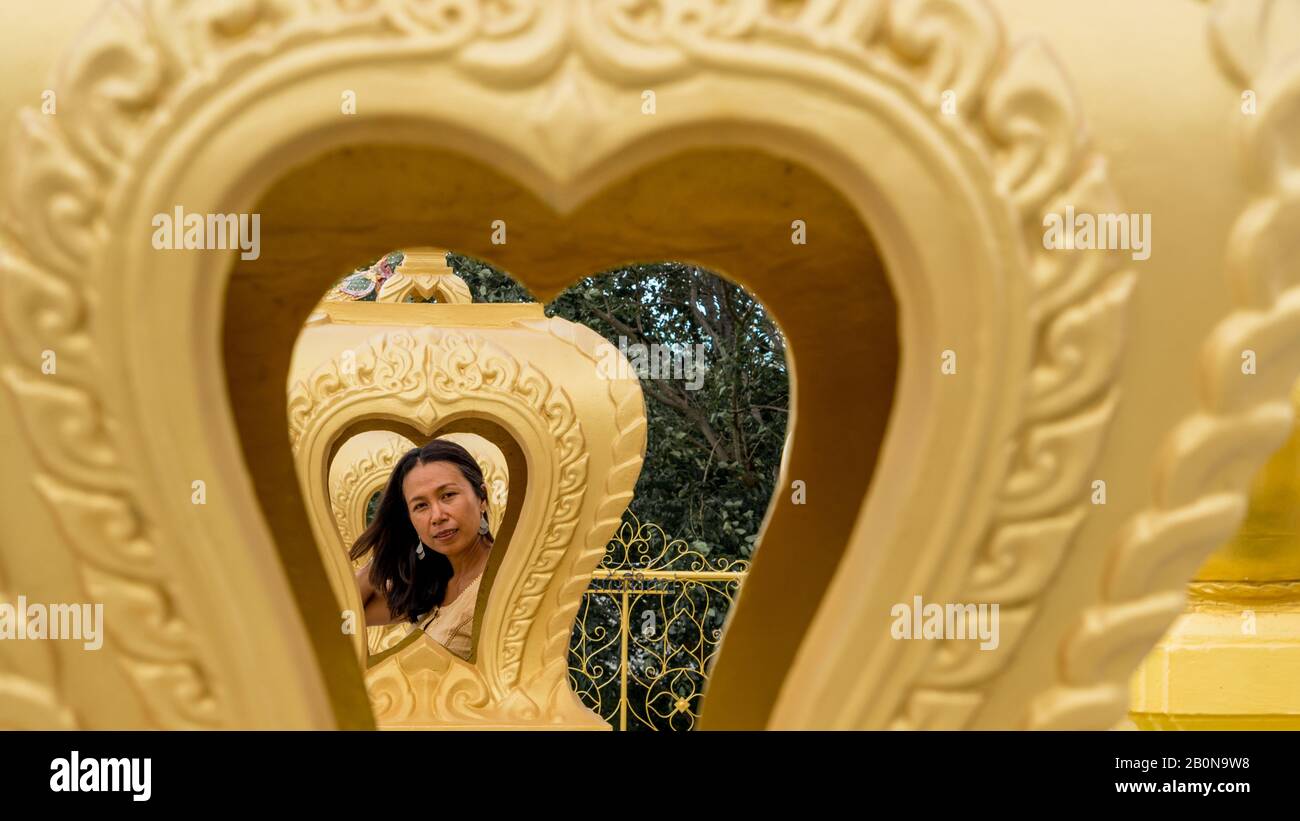 Donna tailandese incorniciata da più cuori d'oro a wat in Pak Nam Pran Foto Stock