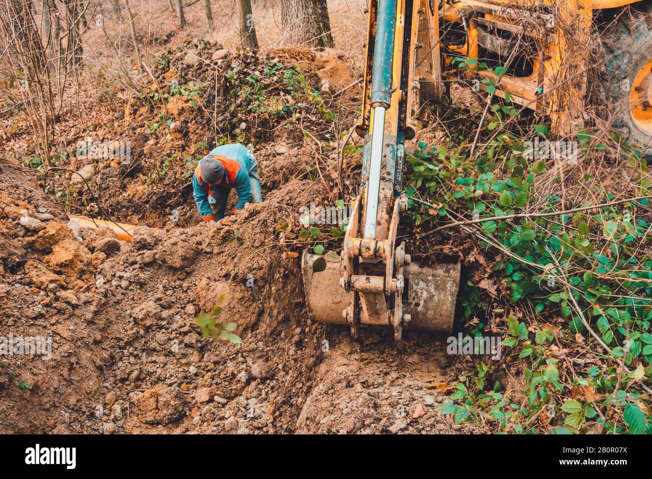 Un escavatore nella foresta scava una siviera per l'allevamento del pesce. Foto Stock