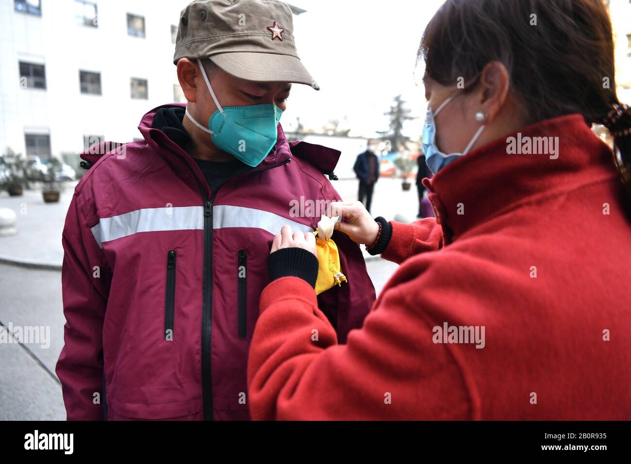 XI'an, la Provincia Shaanxi della Cina. 21st Feb, 2020. La moglie del membro della squadra medica Yang Shuanzhu indossa una bustina per lui a Xi'an, nella provincia Shaanxi della Cina nord-occidentale, 21 febbraio 2020. Il secondo lotto di medicina cinese tradizionale team medico di Shaanxi, formato da 35 personale medico, ha lasciato per Hubei per aiutare il nuovo coronavirus controllo sforzi lì. Credito: Zhang Bowen/Xinhua/Alamy Live News Foto Stock