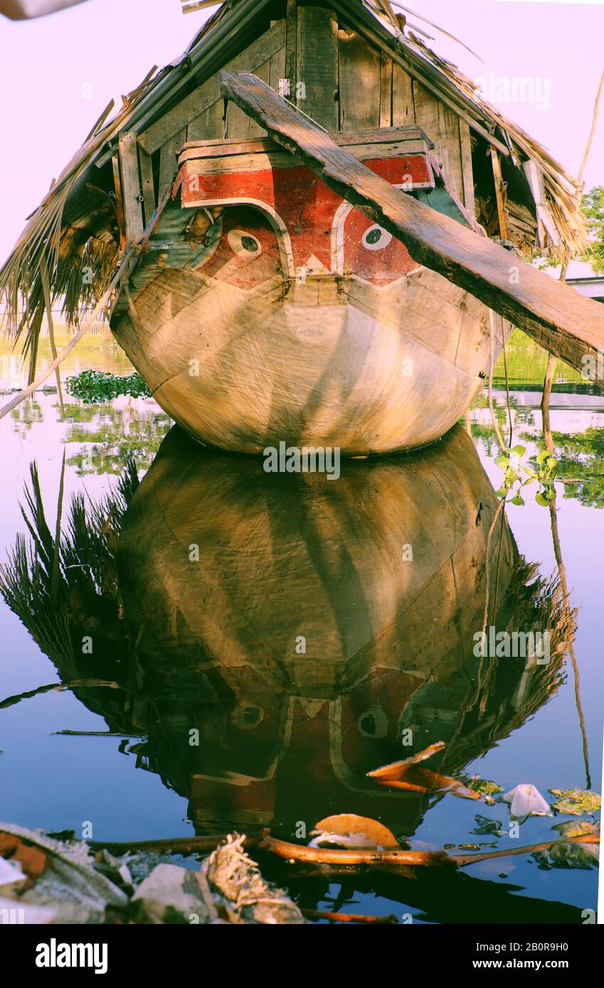 HO chi MINH CITTÀ, VIET NAM, incredibile barca in legno con foglie essiccate tetto ormeggio al fiume, vicino gli occhi barca guardando dritto, barca riflettere sull'acqua Foto Stock