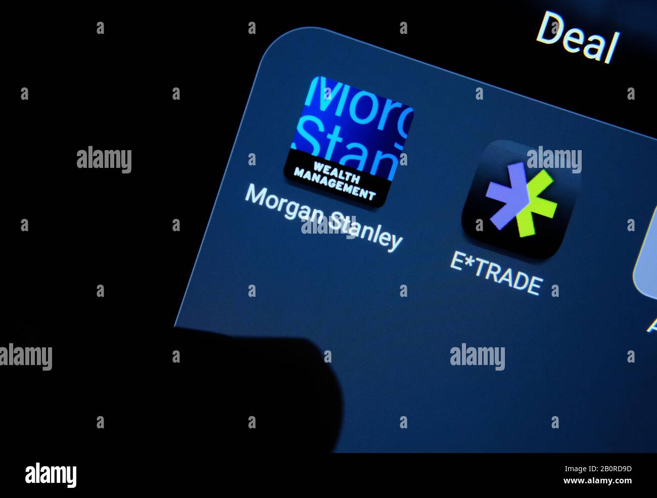 Morgan Stanley e le applicazioni di e-trade su uno schermo dello smartphone e con un dito rivolto verso di loro. Concetto di acquisizione aziendale. Foto Stock