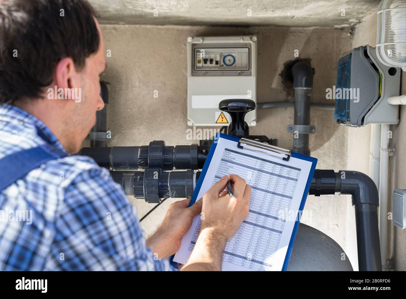 Appunti Di Worker Holding Ispezione Della Pompa Dell'Acqua E Dei Tubi Foto Stock