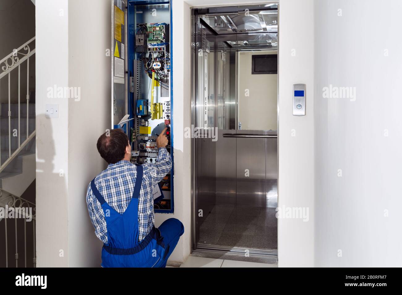 Riparazione Da Parte Del Tecnico Del Pannello Di Controllo Dell'Elevatore Rotto Foto Stock